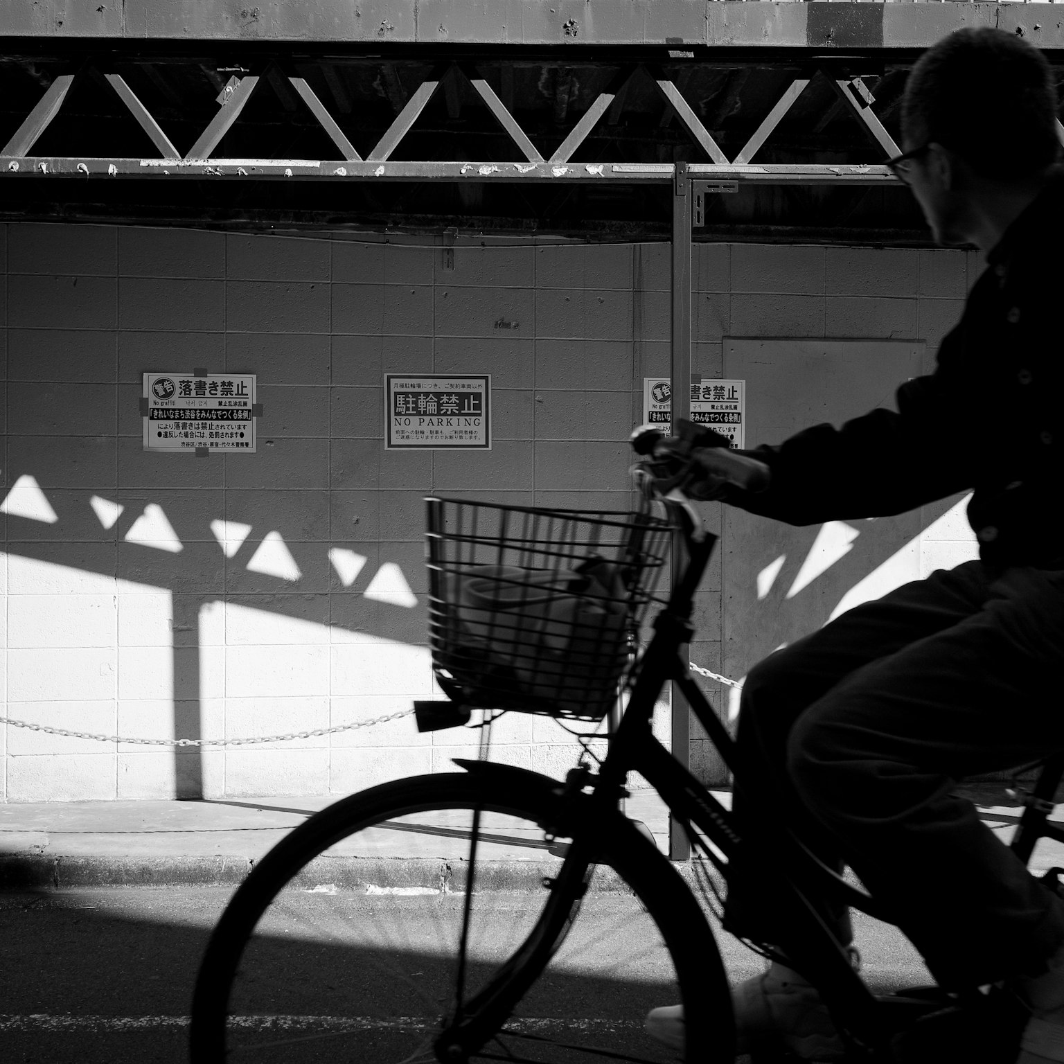 Image en noir et blanc d'une personne à vélo avec des ombres en arrière-plan