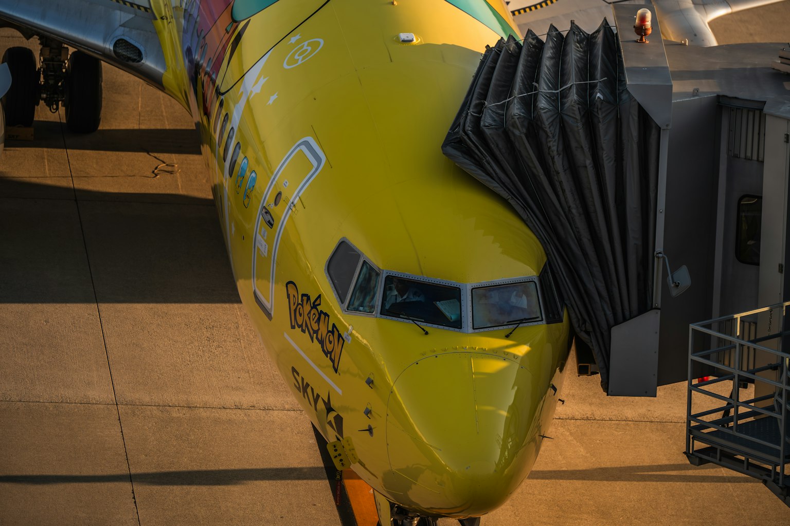 Vista frontal de un avión amarillo en el aeropuerto con pasarela de embarque