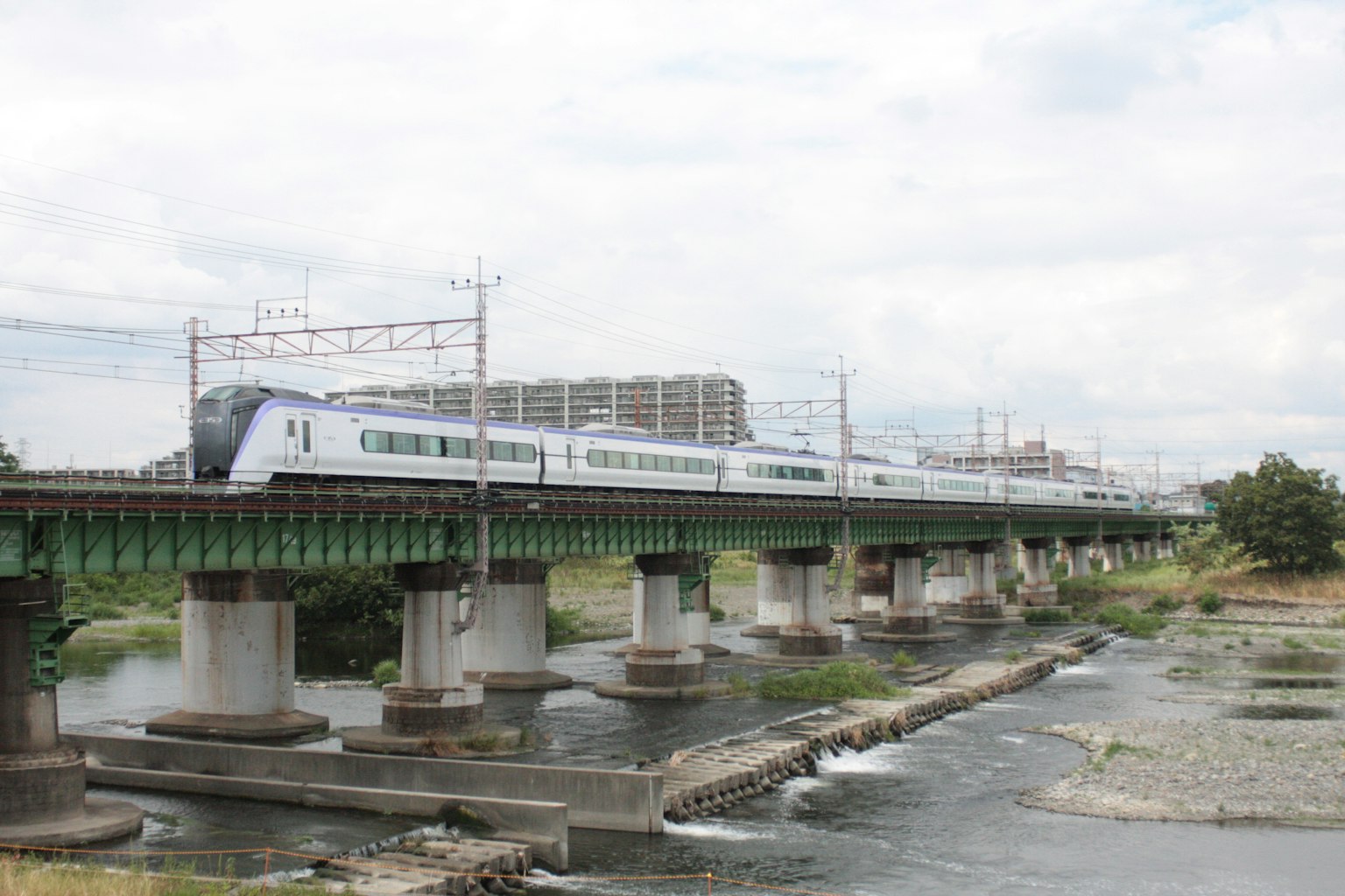 Shinkansen-Zug überquert einen Fluss mit umliegender Landschaft
