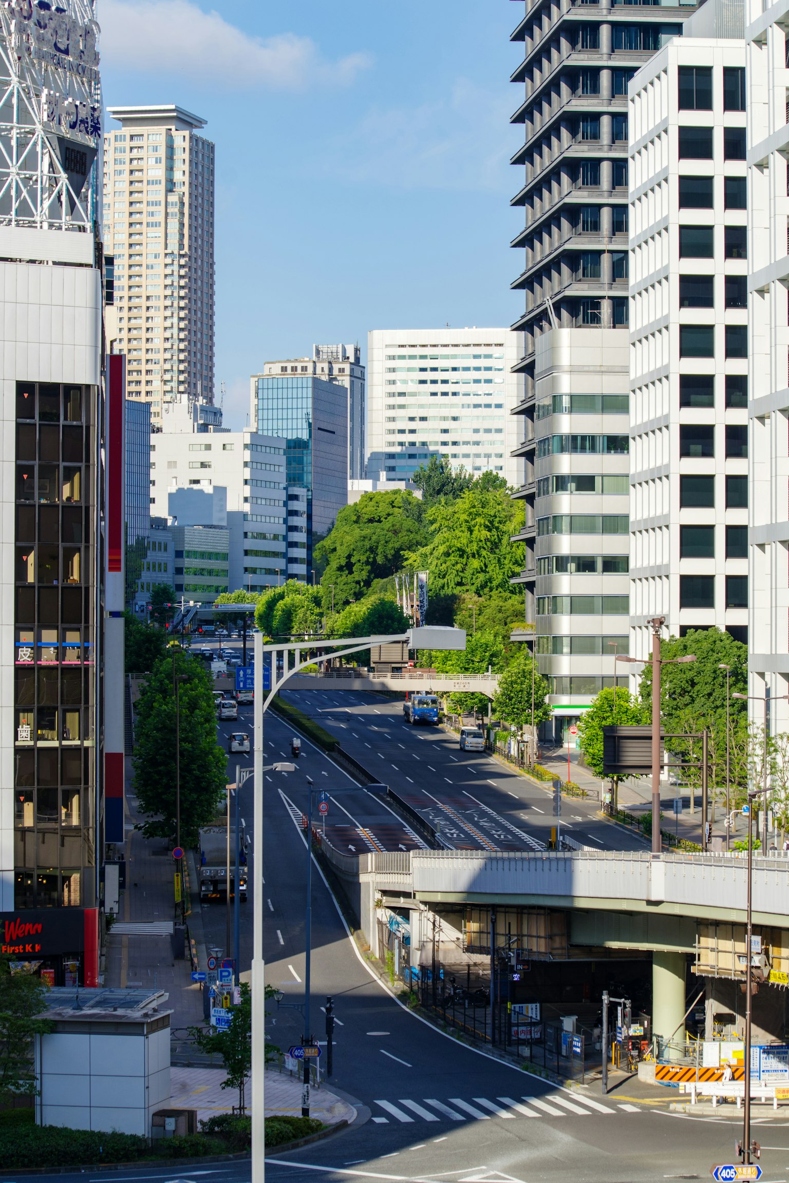 Vista dello skyline di Tokyo con alti edifici e cielo blu chiaro che mostra una strada vuota