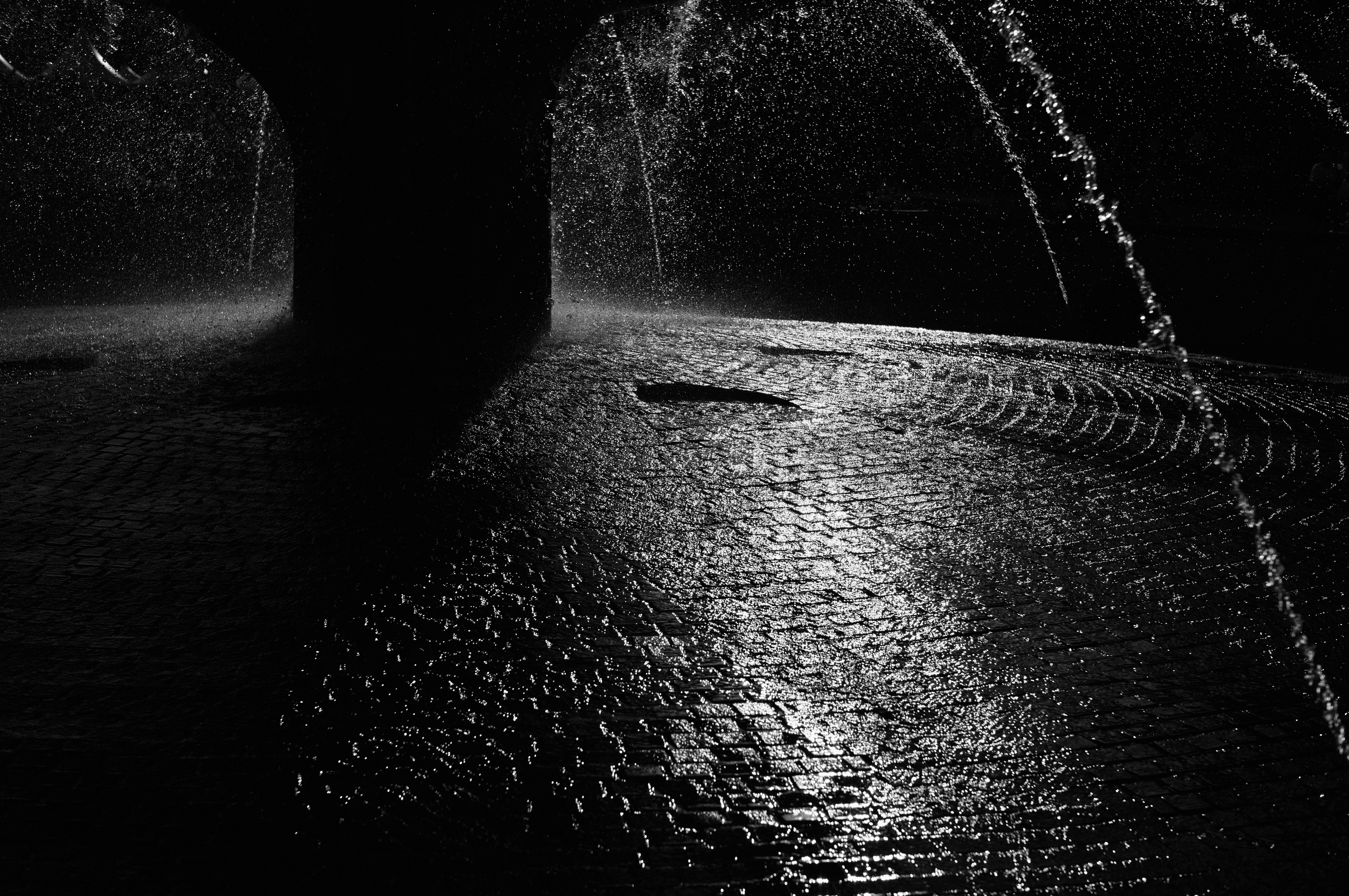 雨中的昏暗隧道地面，水洼与流水