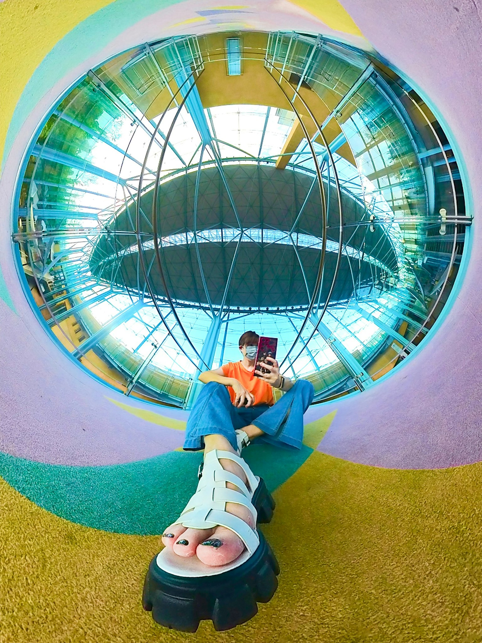 Uno sfondo colorato con uno specchio grande che riflette una persona che scatta un selfie