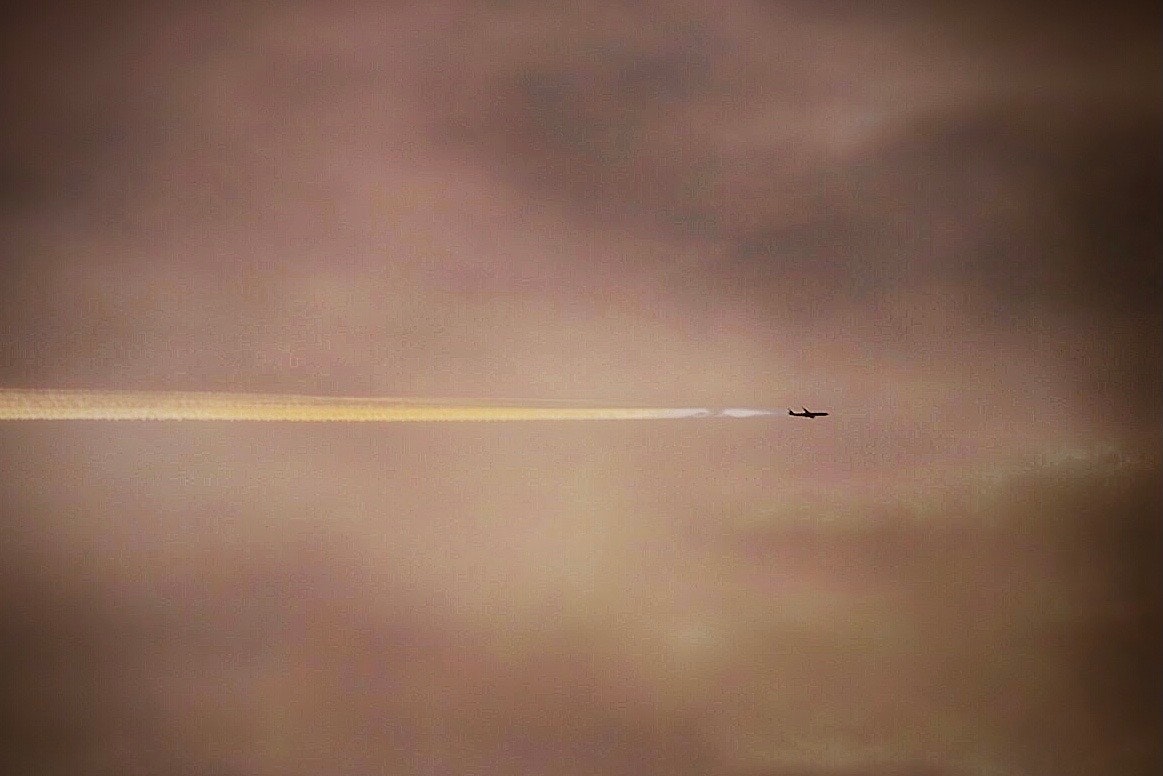 夕暮れの空に伸びる飛行機雲の一直線