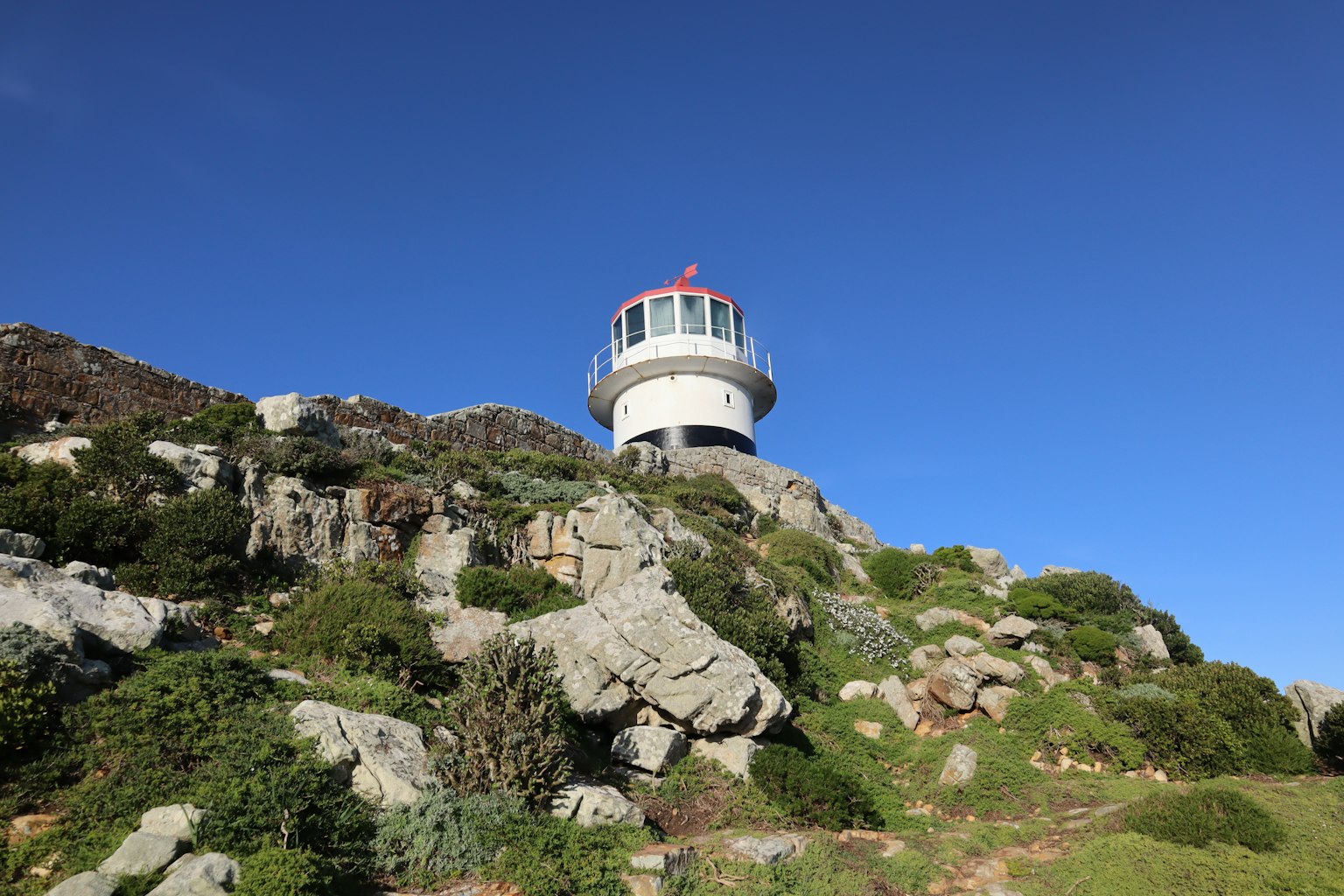 Phare sur un terrain rocheux sous un ciel bleu clair