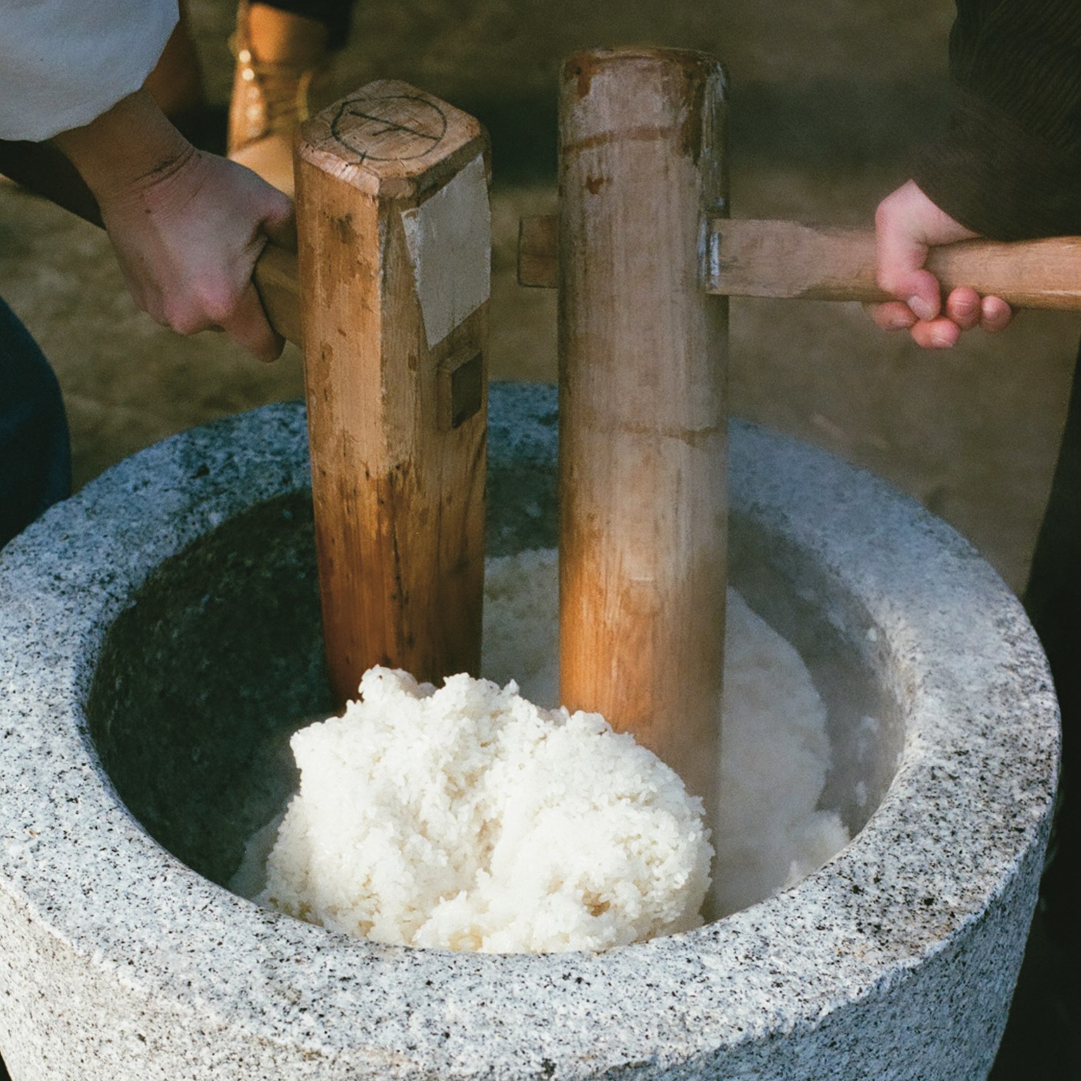 Escena tradicional de golpear arroz para hacer mochi con morteros de madera