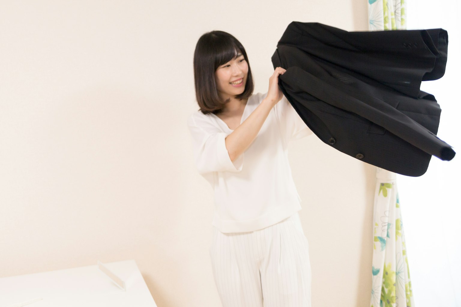 A woman holding a black garment in an indoor setting