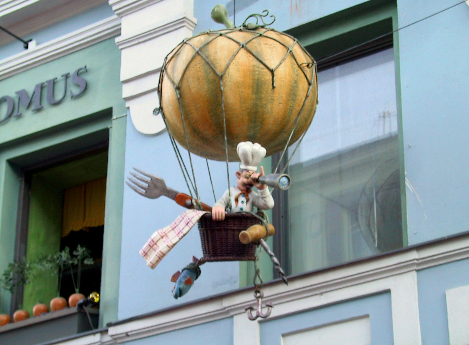 Ein fantasievisches Schild mit einer Chef-Figur in einem Heißluftballon in Form einer Kürbis