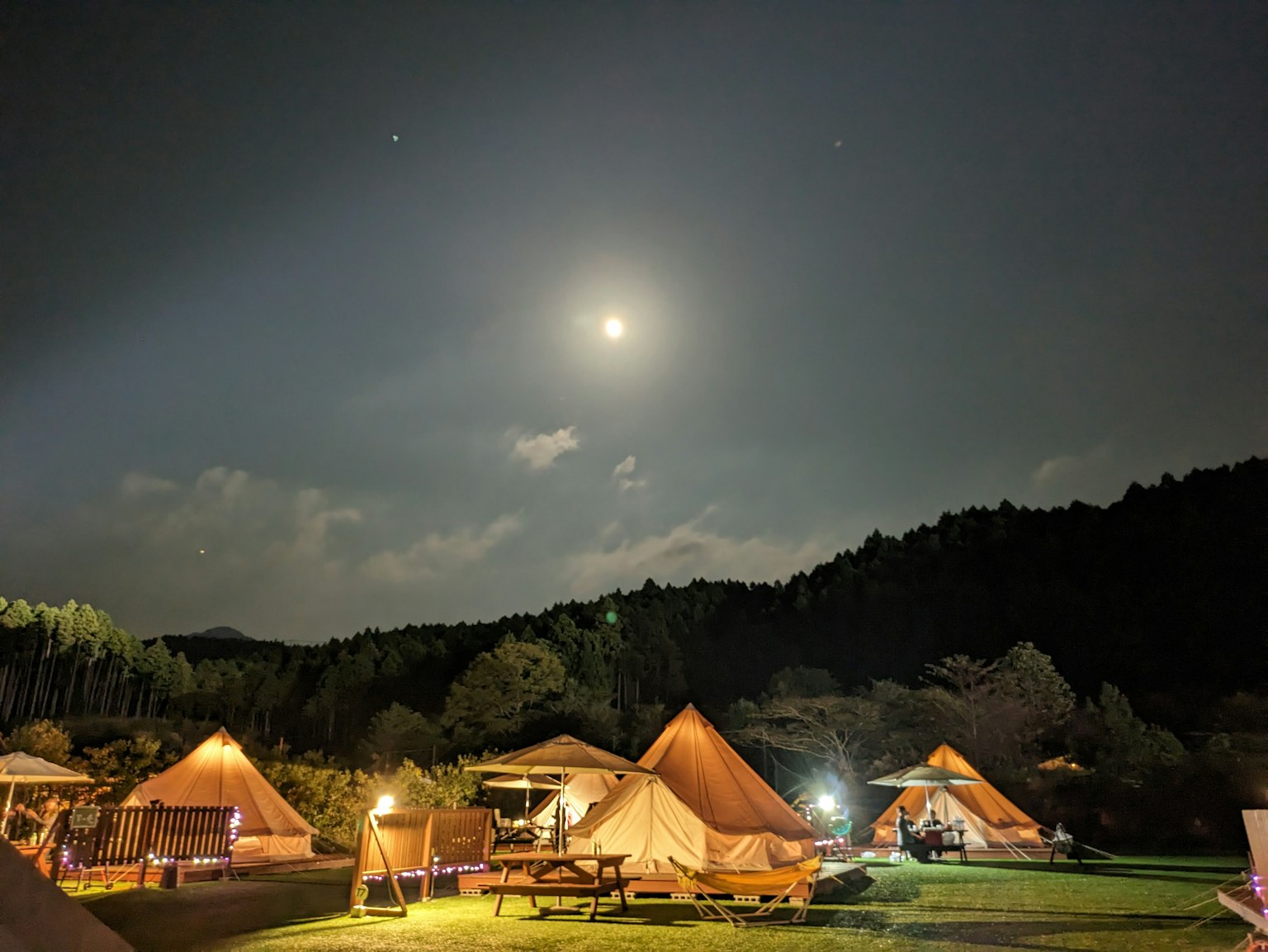Camping tents under a night sky with a bright moon