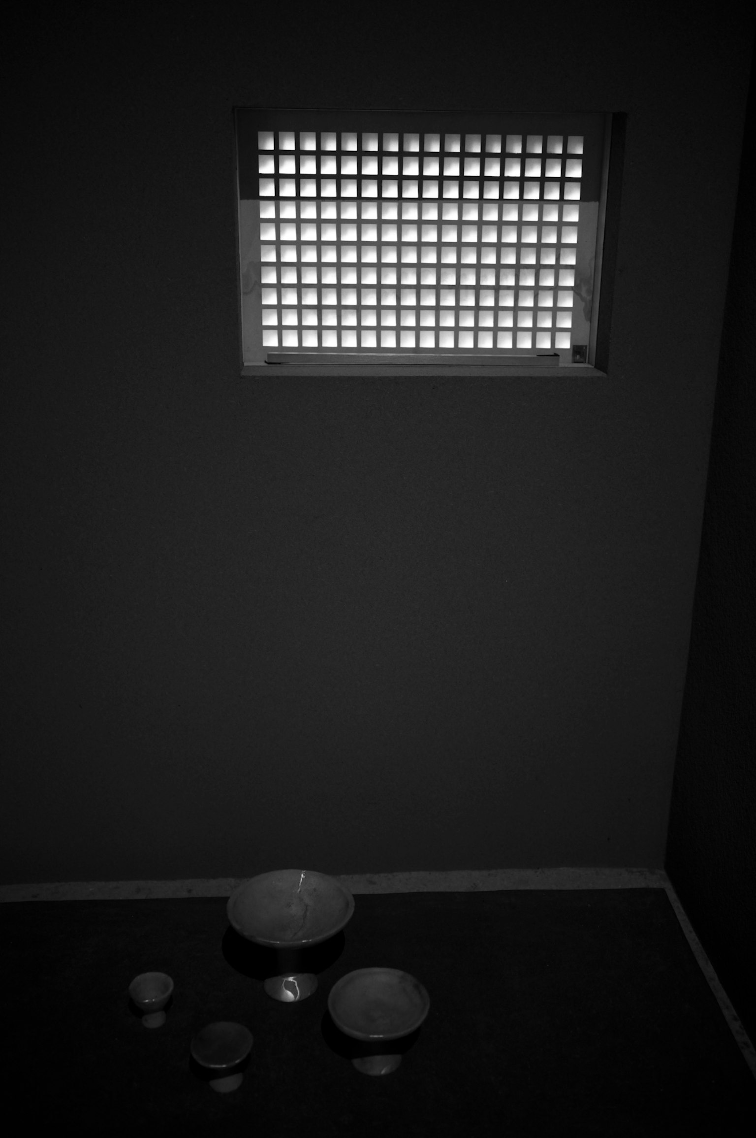 Dark room with white ceramic bowls and light coming through a window
