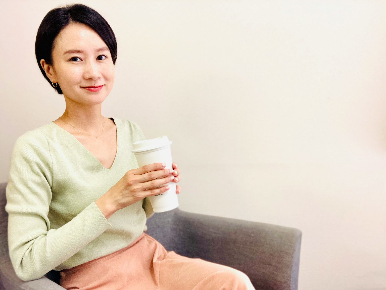 Một người phụ nữ cầm cốc cà phê mặc áo len