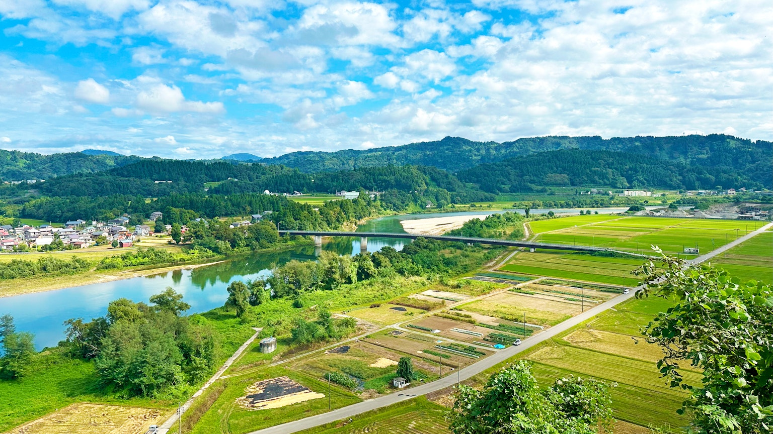 Khung cảnh thơ mộng của một dòng sông và đồng ruộng xanh tươi dưới bầu trời xanh lam