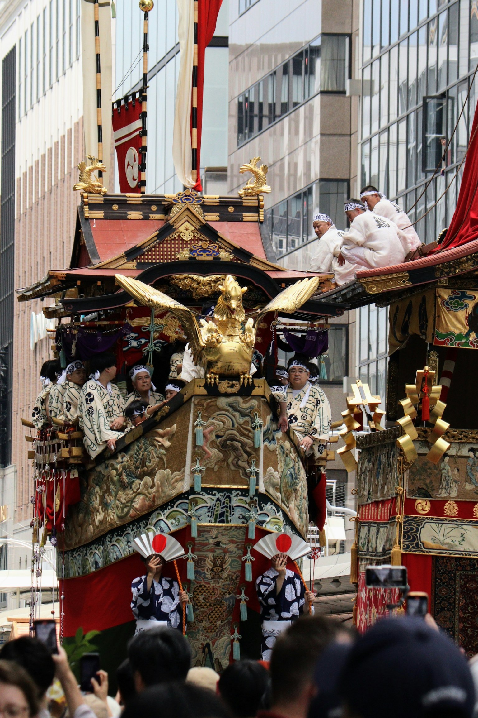 传统节日花车在城市游行，金色装饰和参与者可见