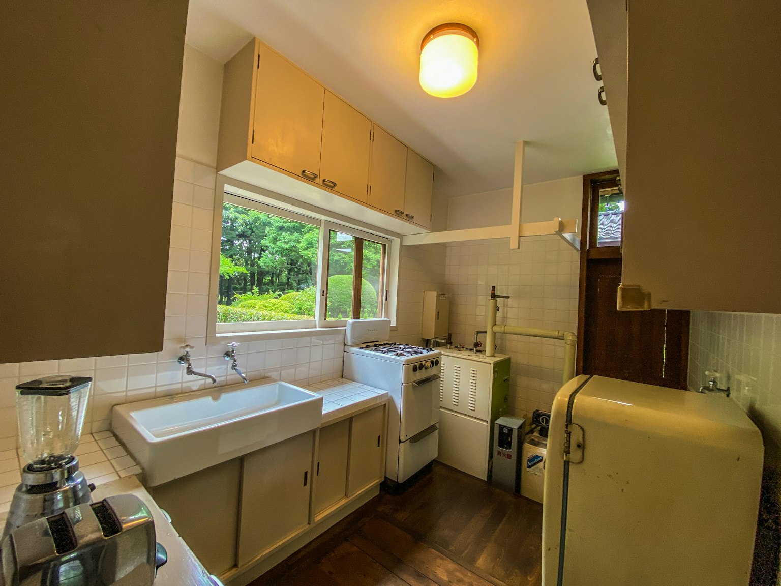 Nội thất bếp sáng với ánh sáng tự nhiên từ cửa sổ tủ đơn giản tủ lạnh cổ điển bồn rửa và máy giặt
