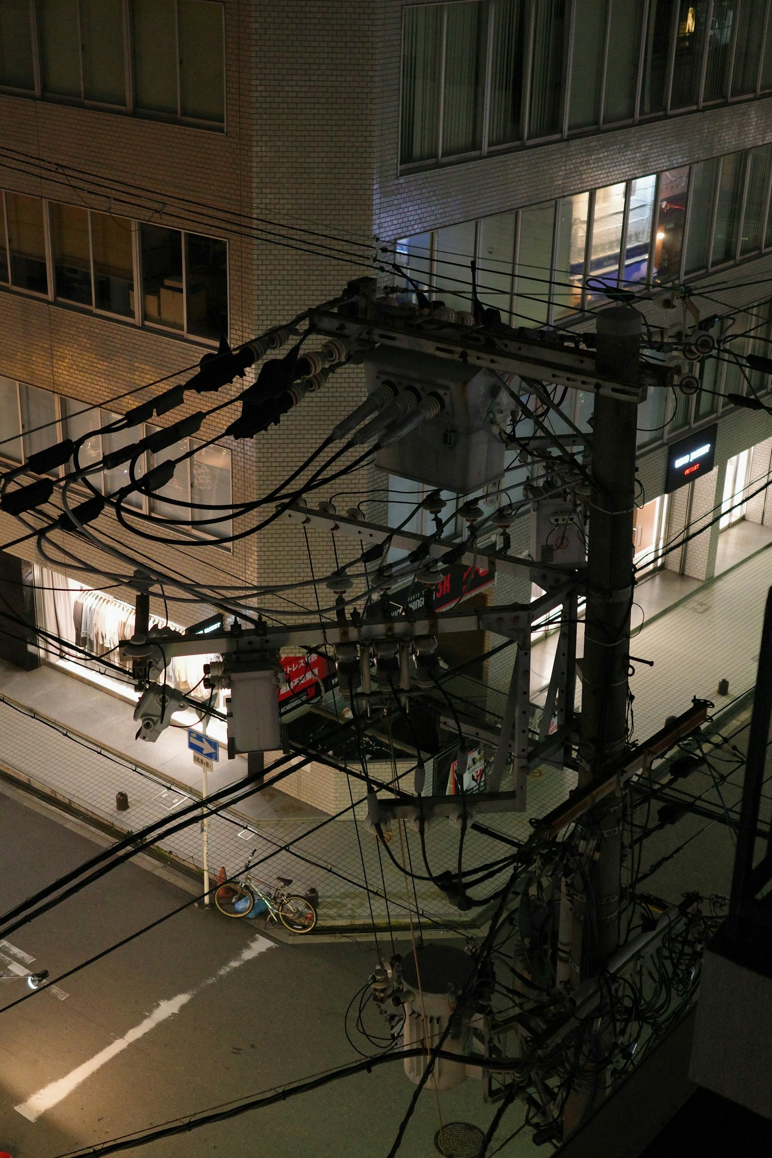 Vista notturna di pali elettrici e linee con una strada cittadina