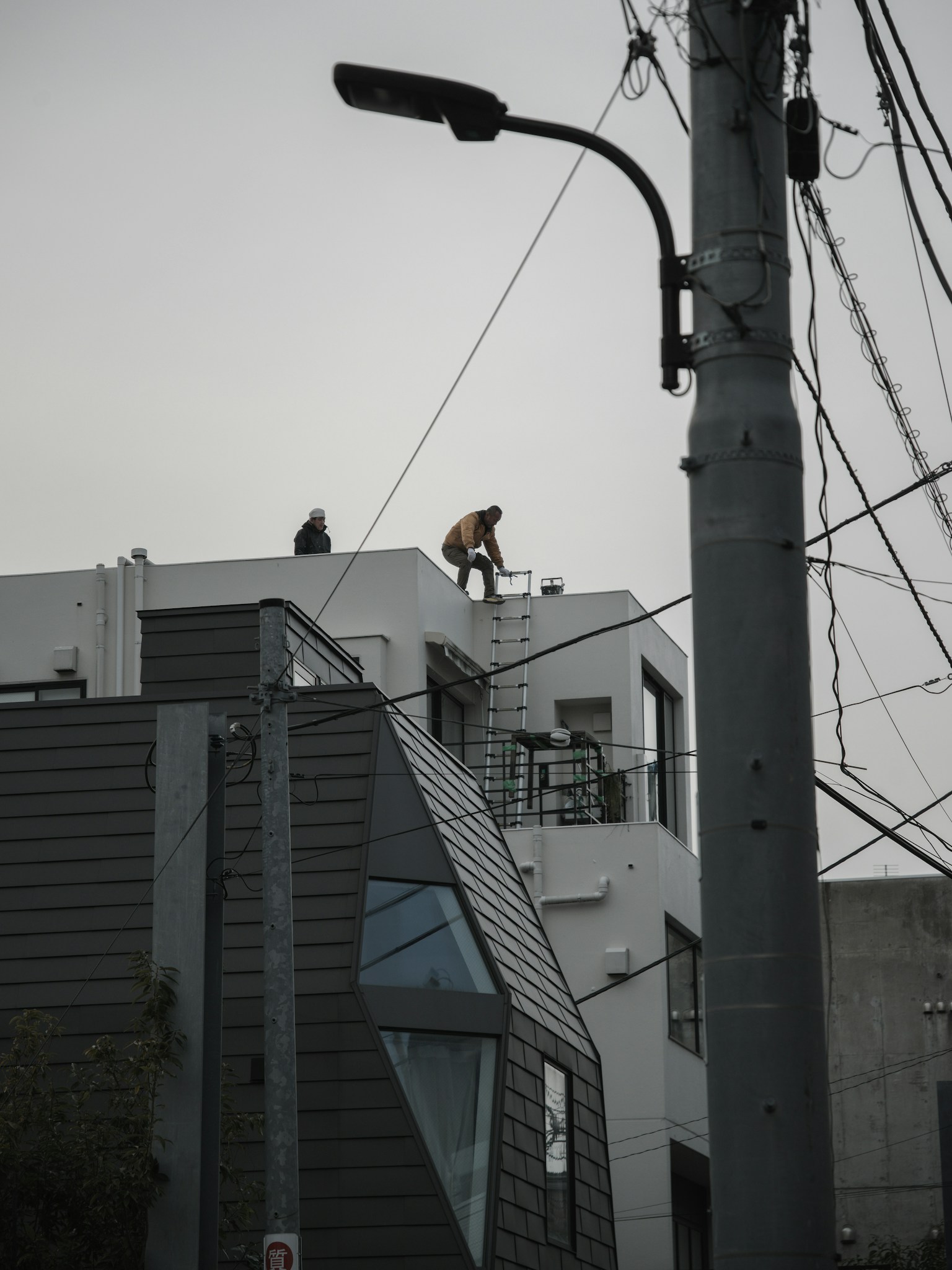 屋顶上工作的人与背景中建筑物和灰色天空的图像