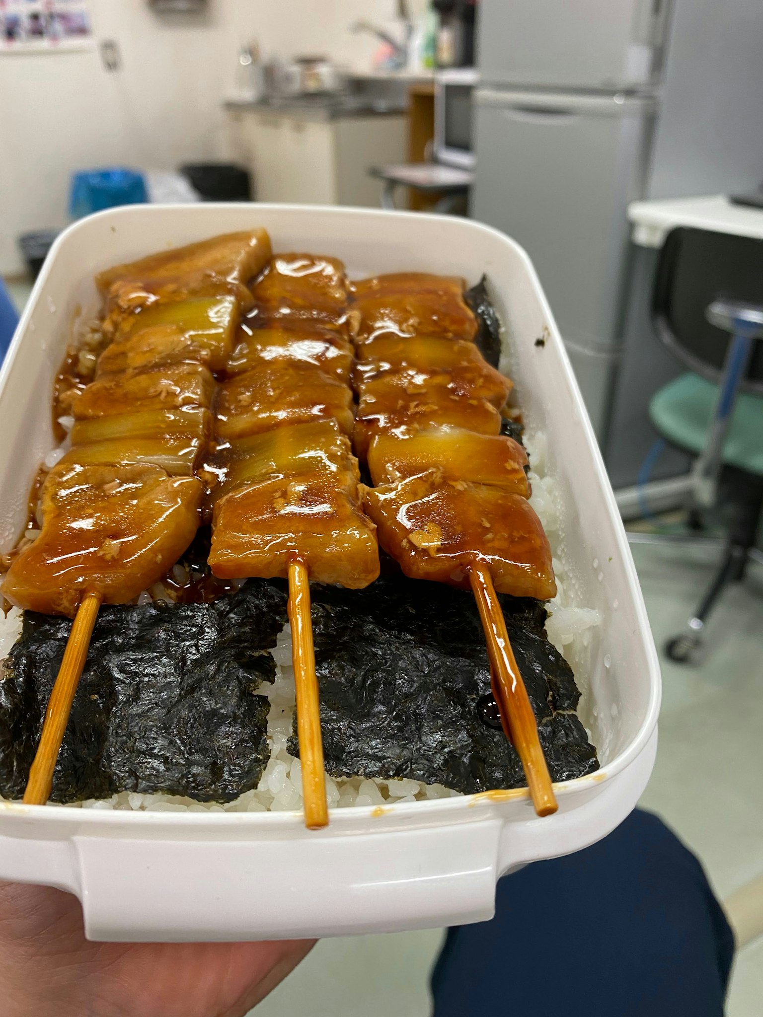 Spiedini di pollo grigliati su riso in una scatola bento bianca