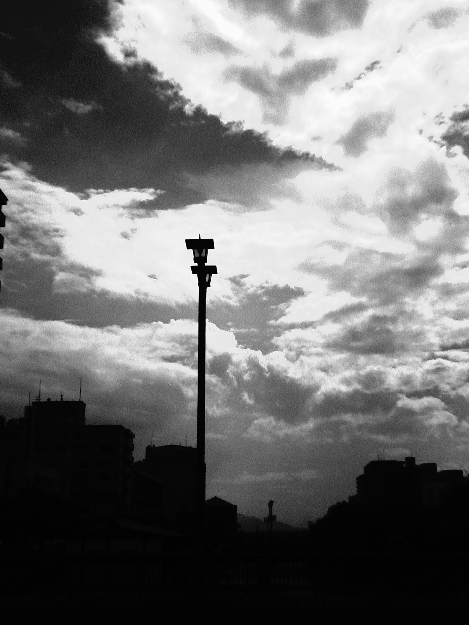 Silueta de una farola contra un cielo dramático en blanco y negro