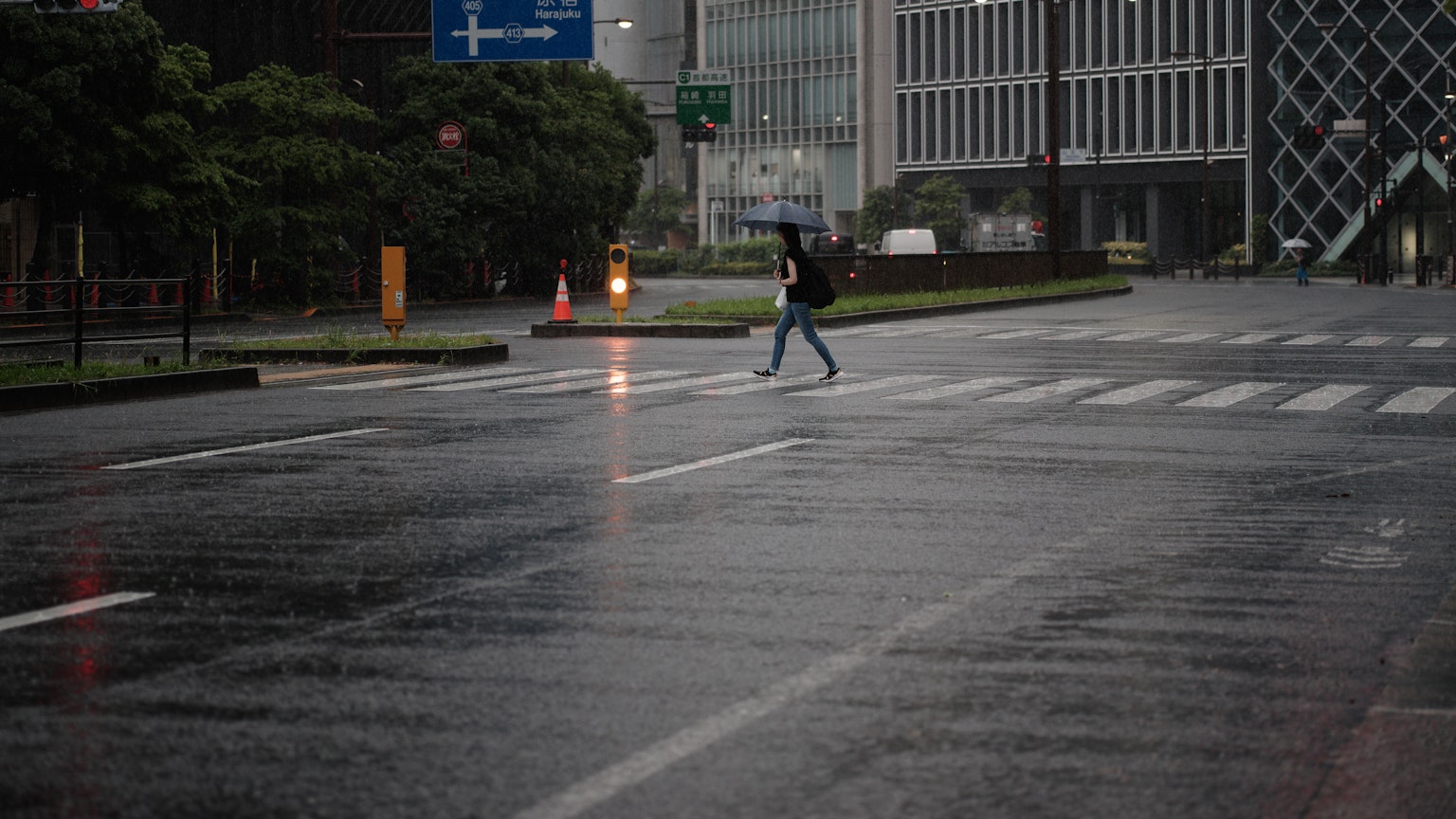 A person crossing a wet crosswalk in the rain