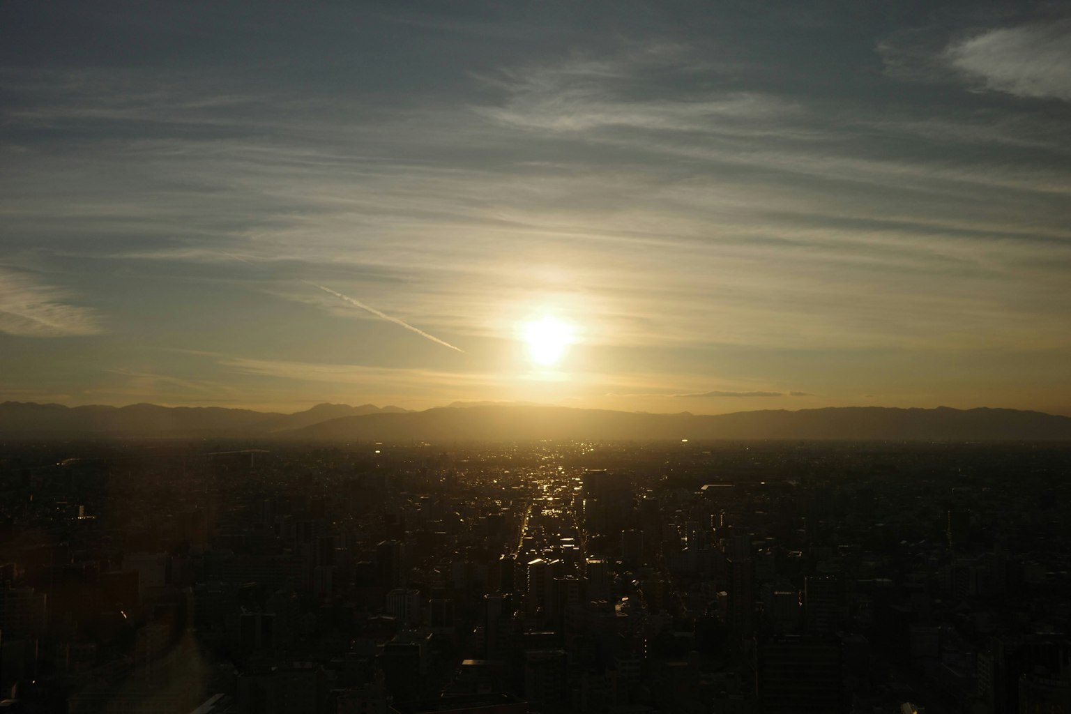 Cảnh quan thành phố lúc hoàng hôn với mặt trời rực rỡ núi xa và mây