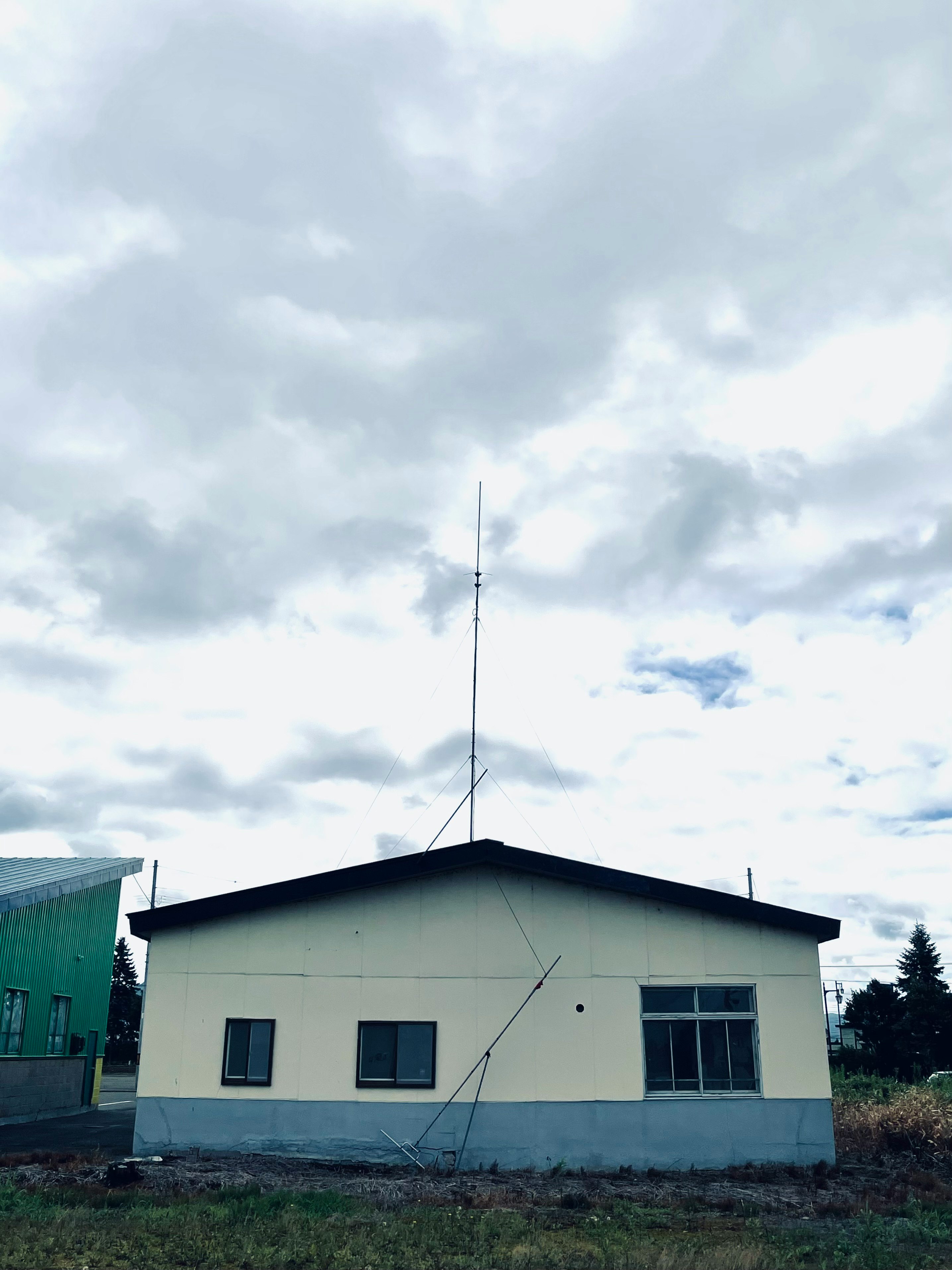 雲の下に立つ三角屋根のアンテナ