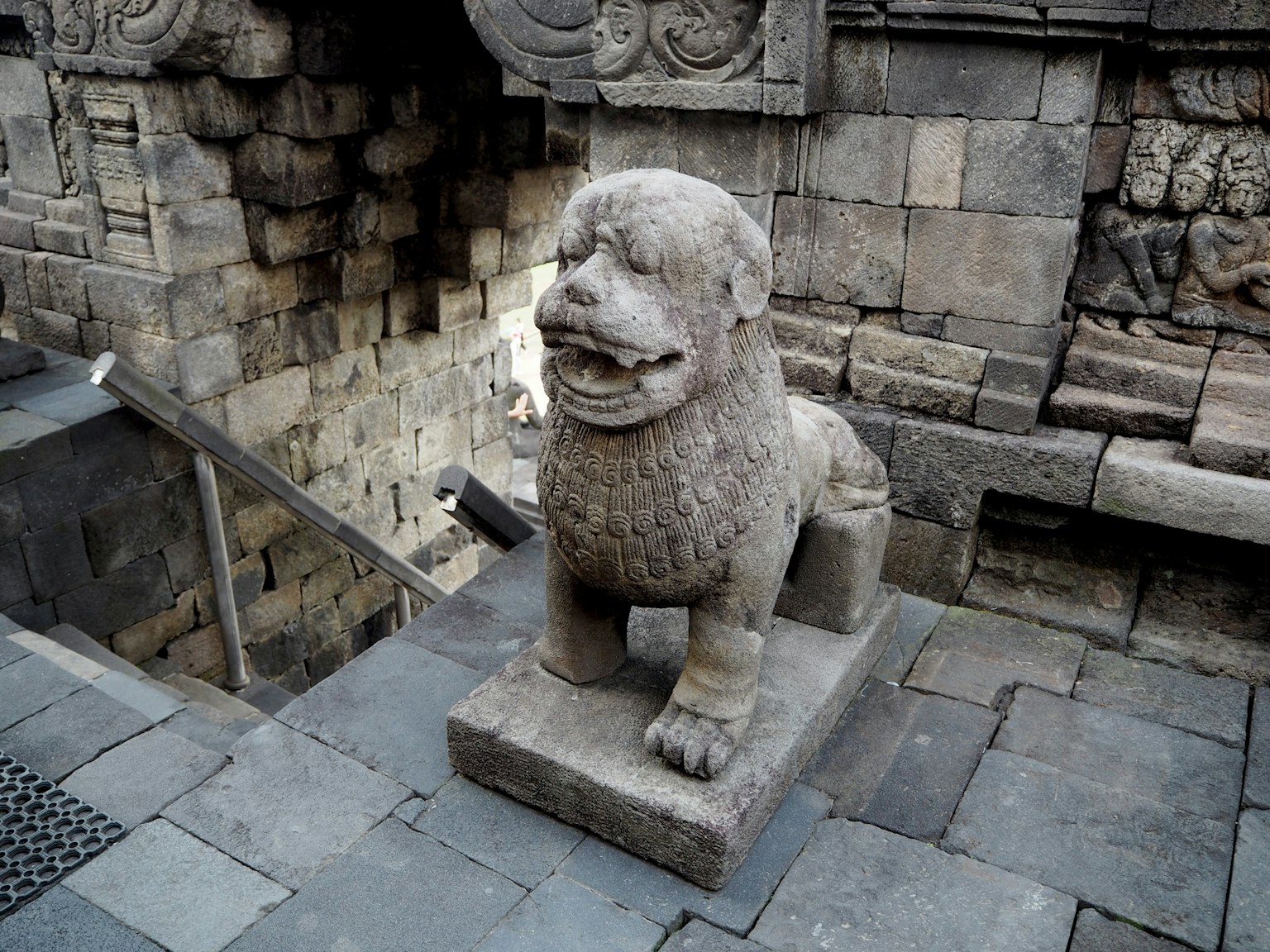 Scultura di leone in pietra antica seduta sui gradini di un tempio