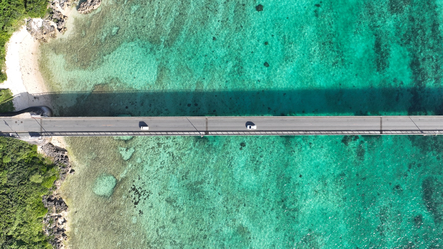 Vista aérea de un puente con coches sobre aguas turquesas