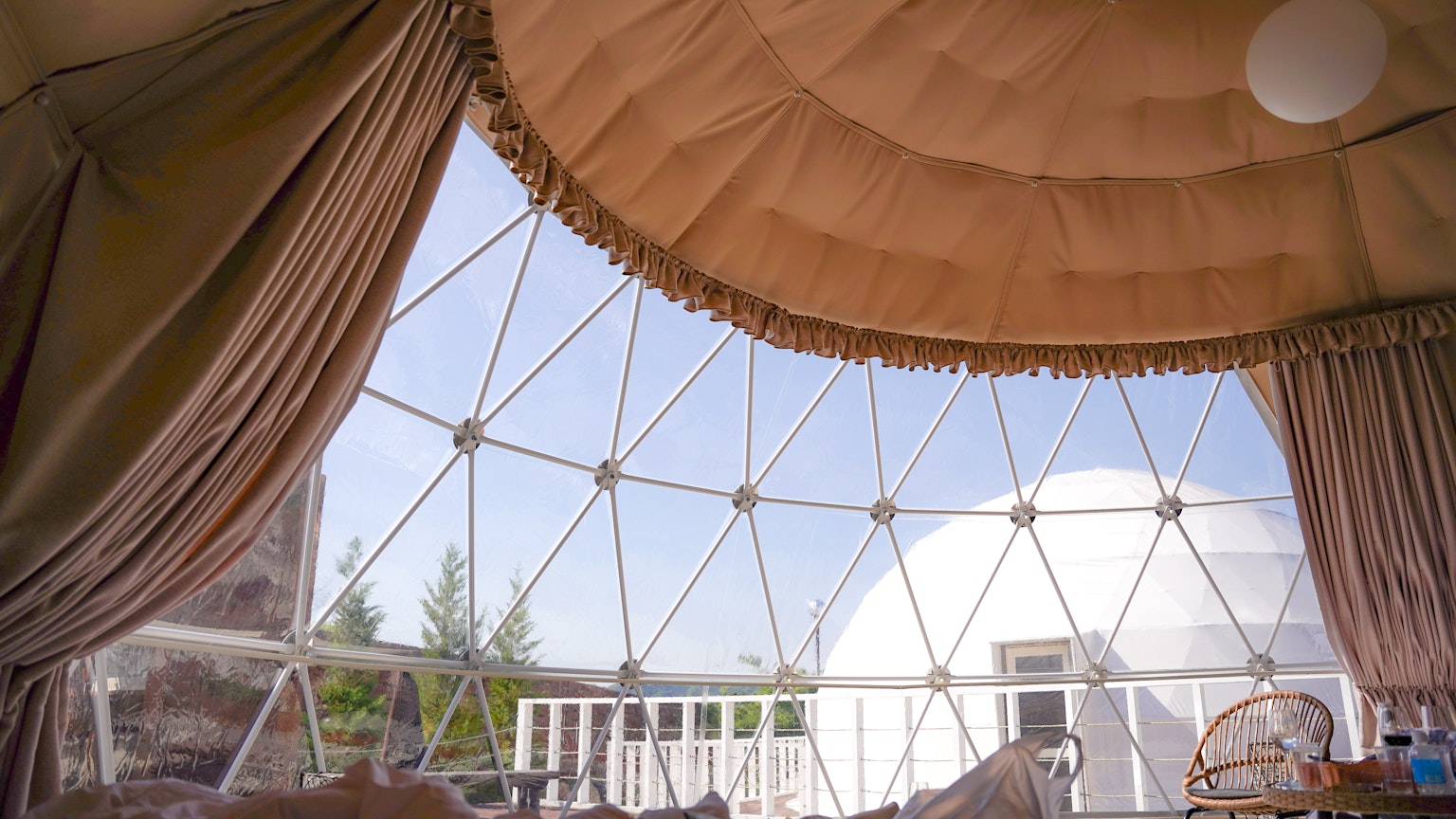 Interior dari dome geodesik menampilkan tirai dan langit cerah