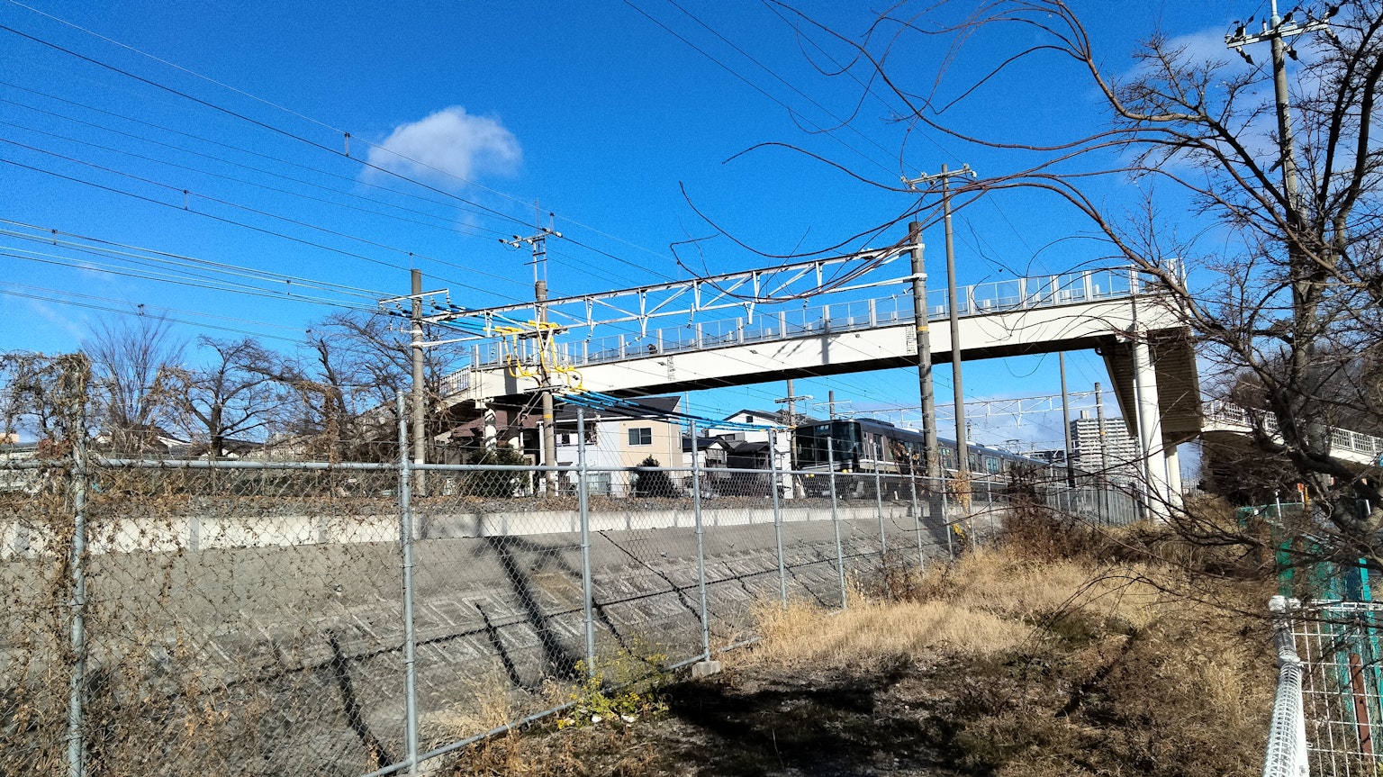 A view of an elevated bridge with power lines under a blue sky