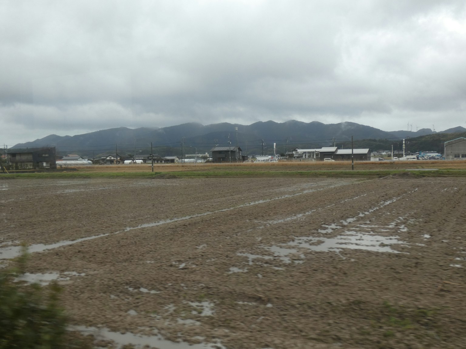 Paisaje con tierras agrícolas y montañas cielo nublado con suelo húmedo