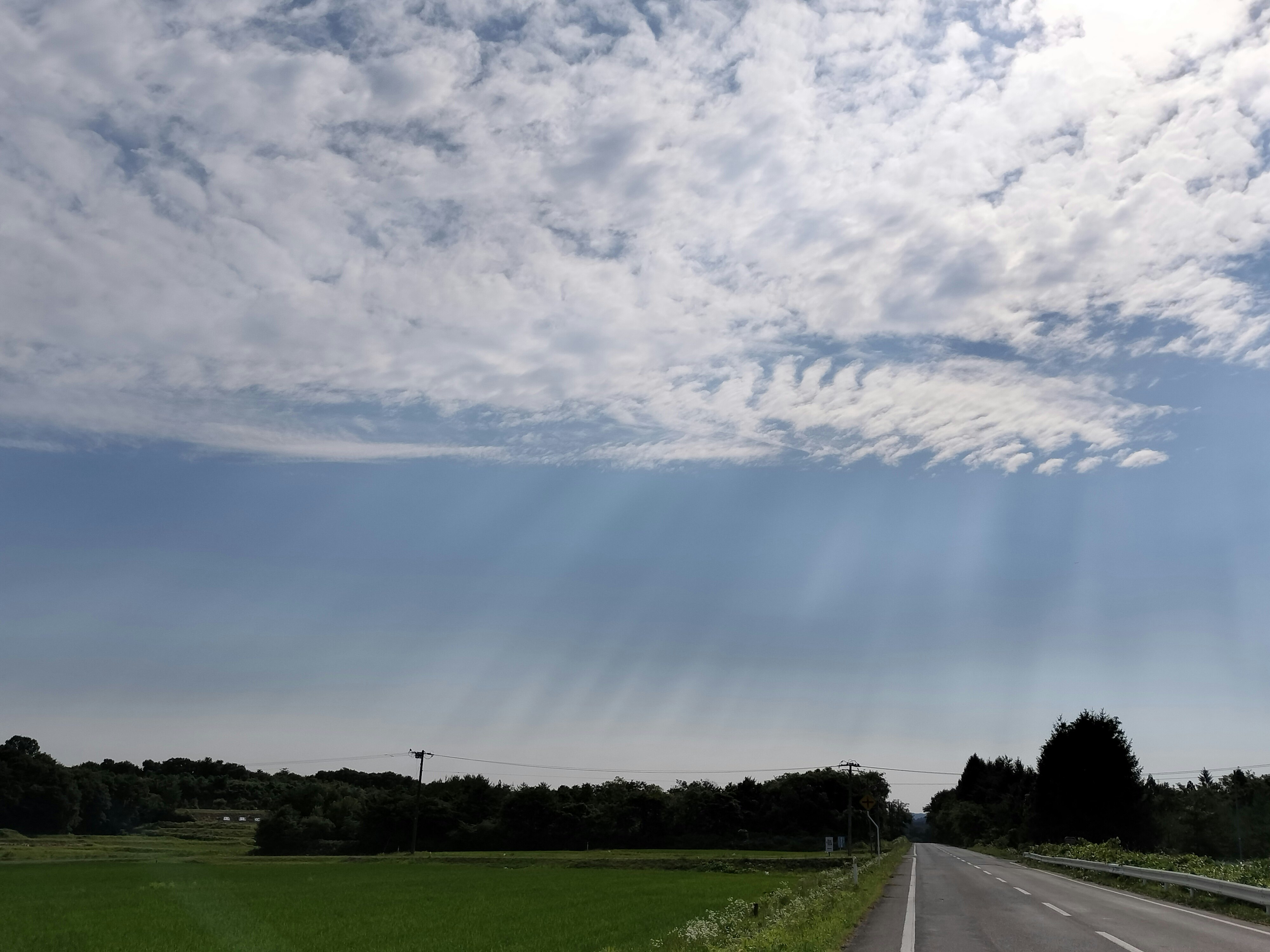 光束照耀的多云天空下的草地与道路景