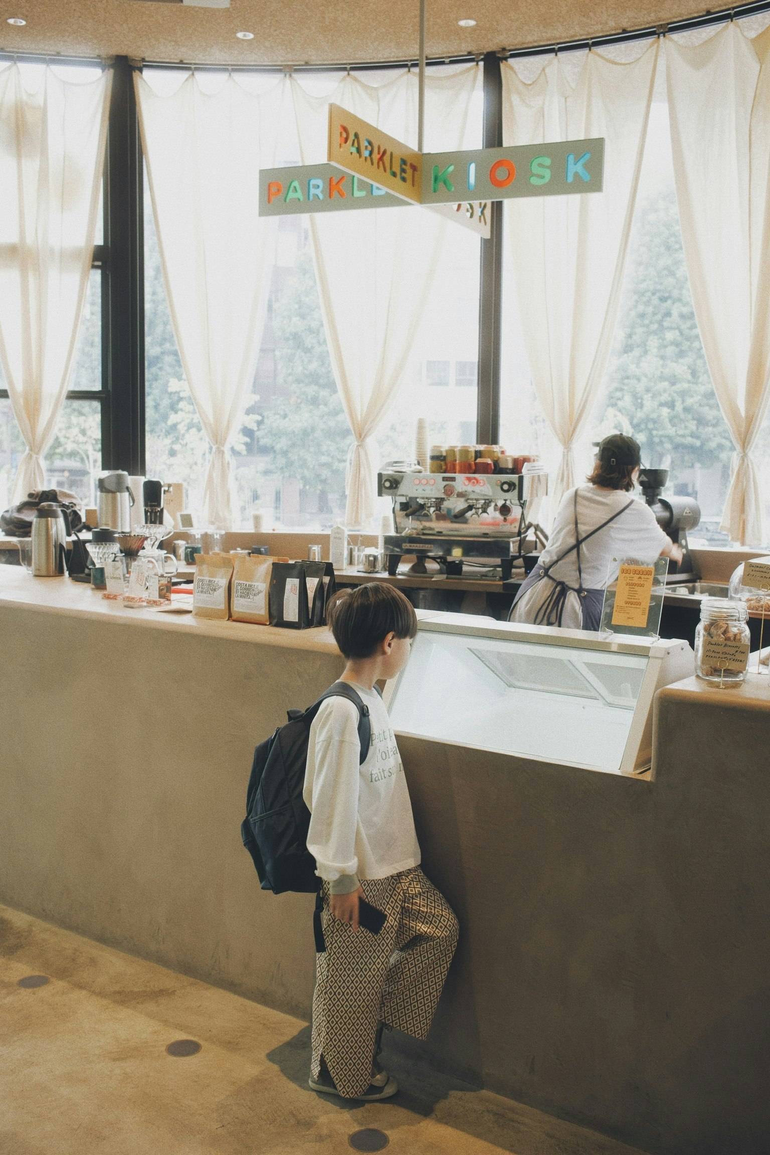 Bambino in attesa al bancone del caffè con il personale sullo sfondo