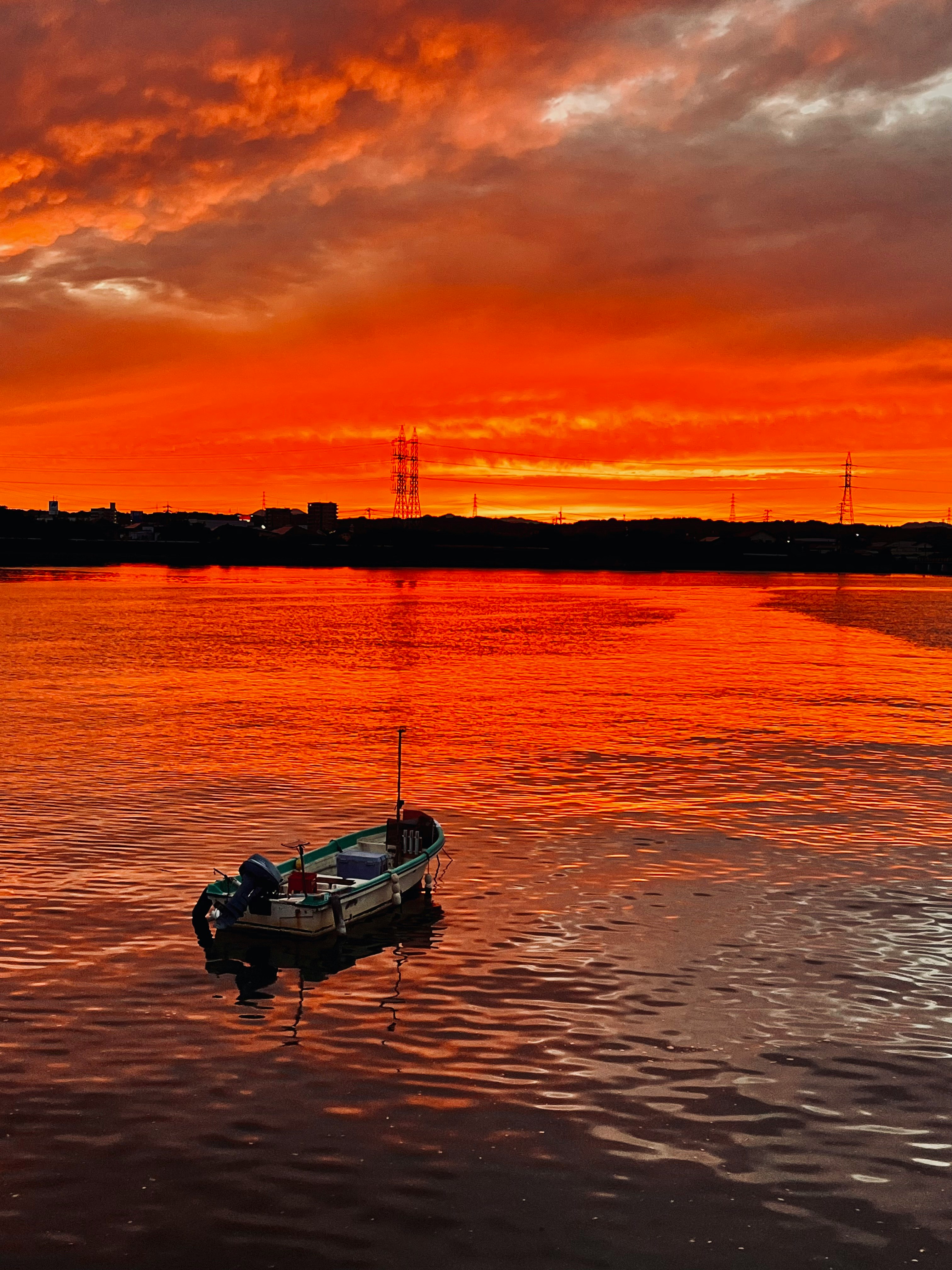 Ein kleines Boot treibt auf ruhigem Wasser unter einem glühenden Sonnenuntergangshimmel