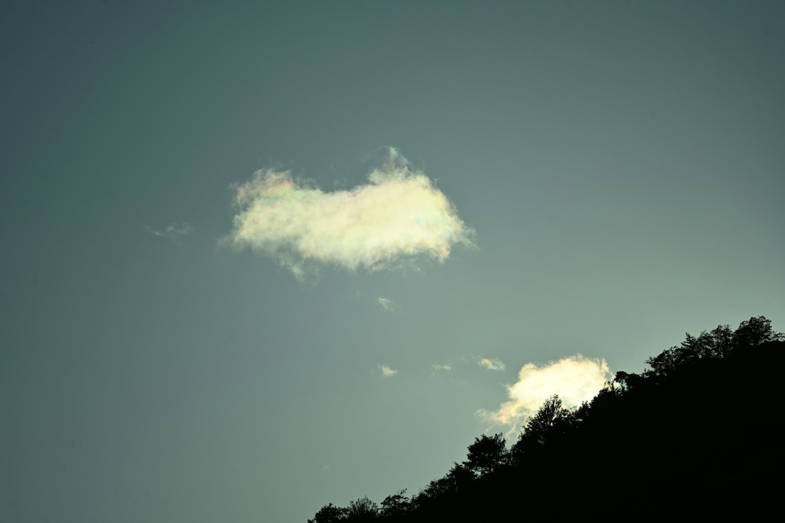 Nuages blancs flottant dans un ciel bleu avec une silhouette de montagnes