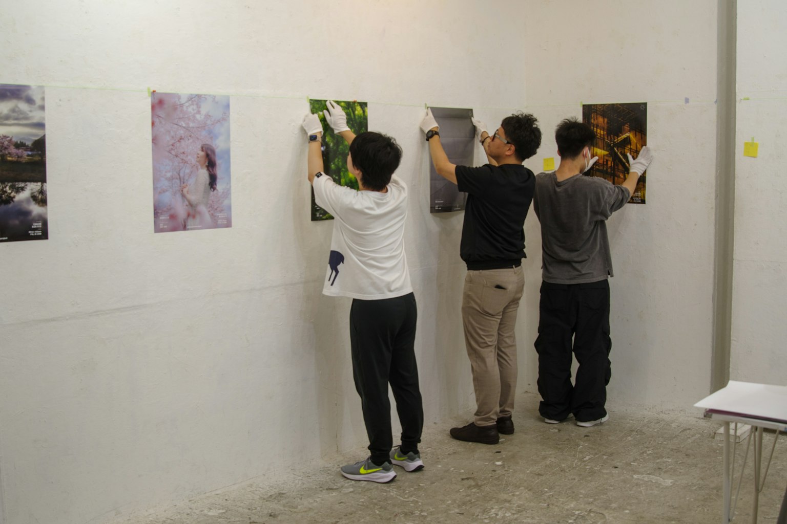 一群人在牆上掛照片為藝術展做準備