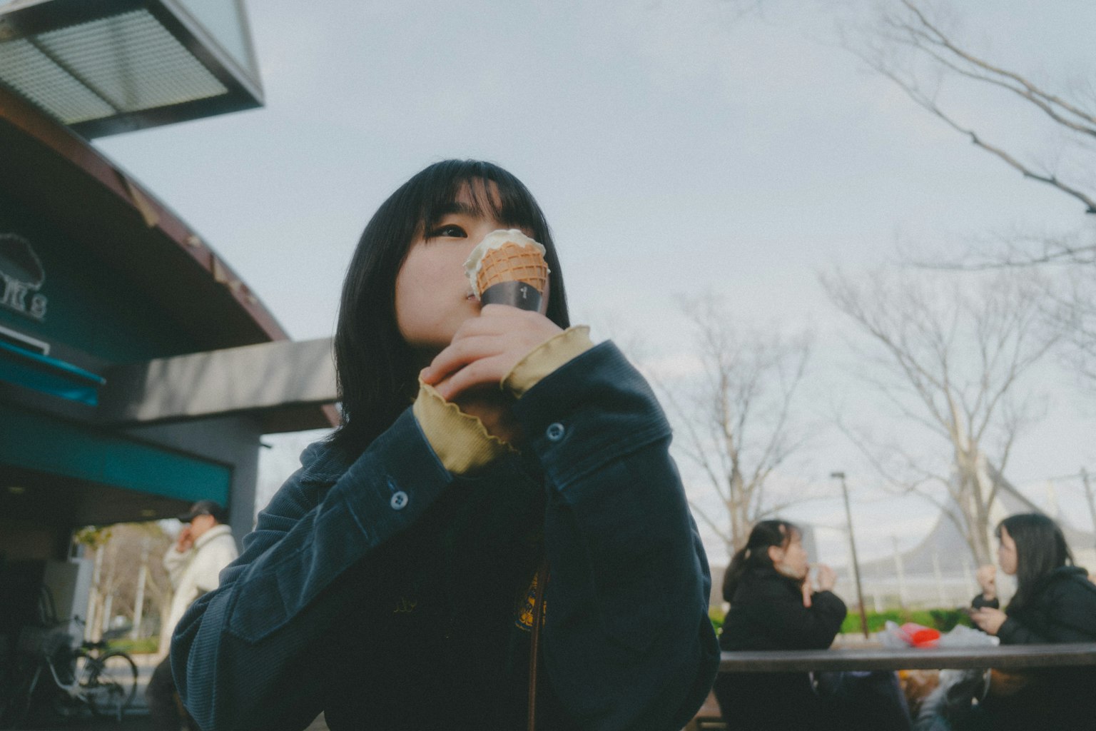 Woman enjoying ice cream in a park with people in the background
