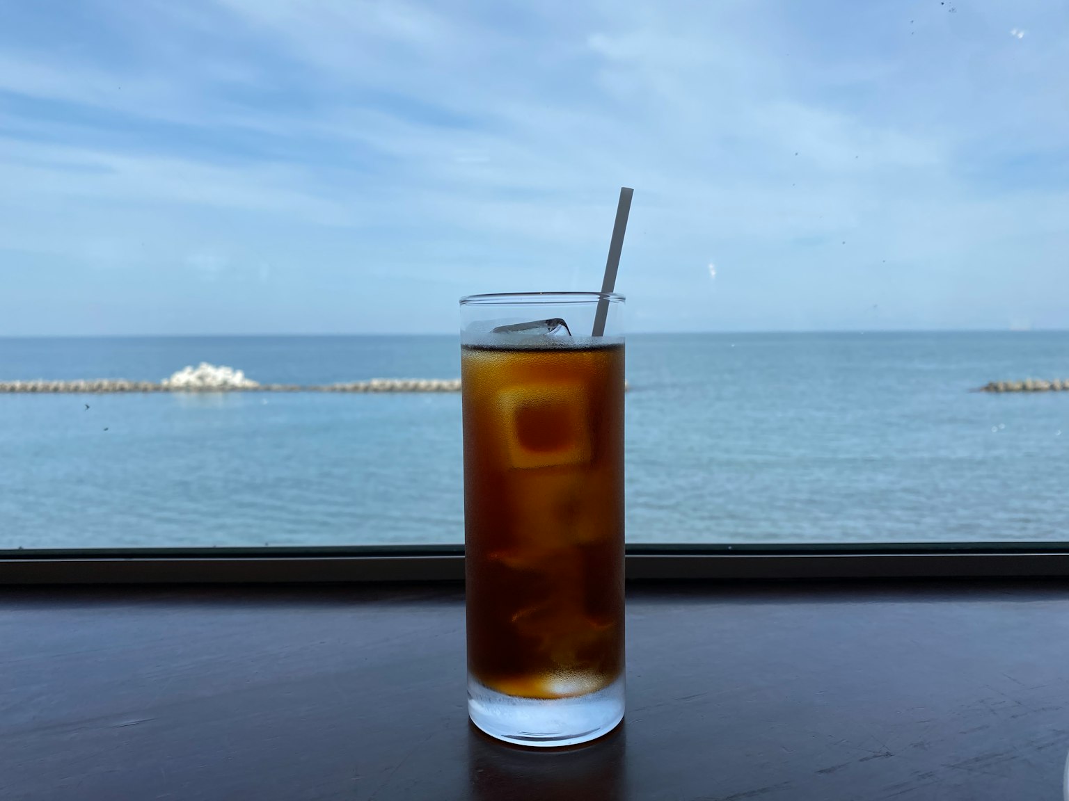Bicchiere di caffè freddo con vista sull'oceano sullo sfondo