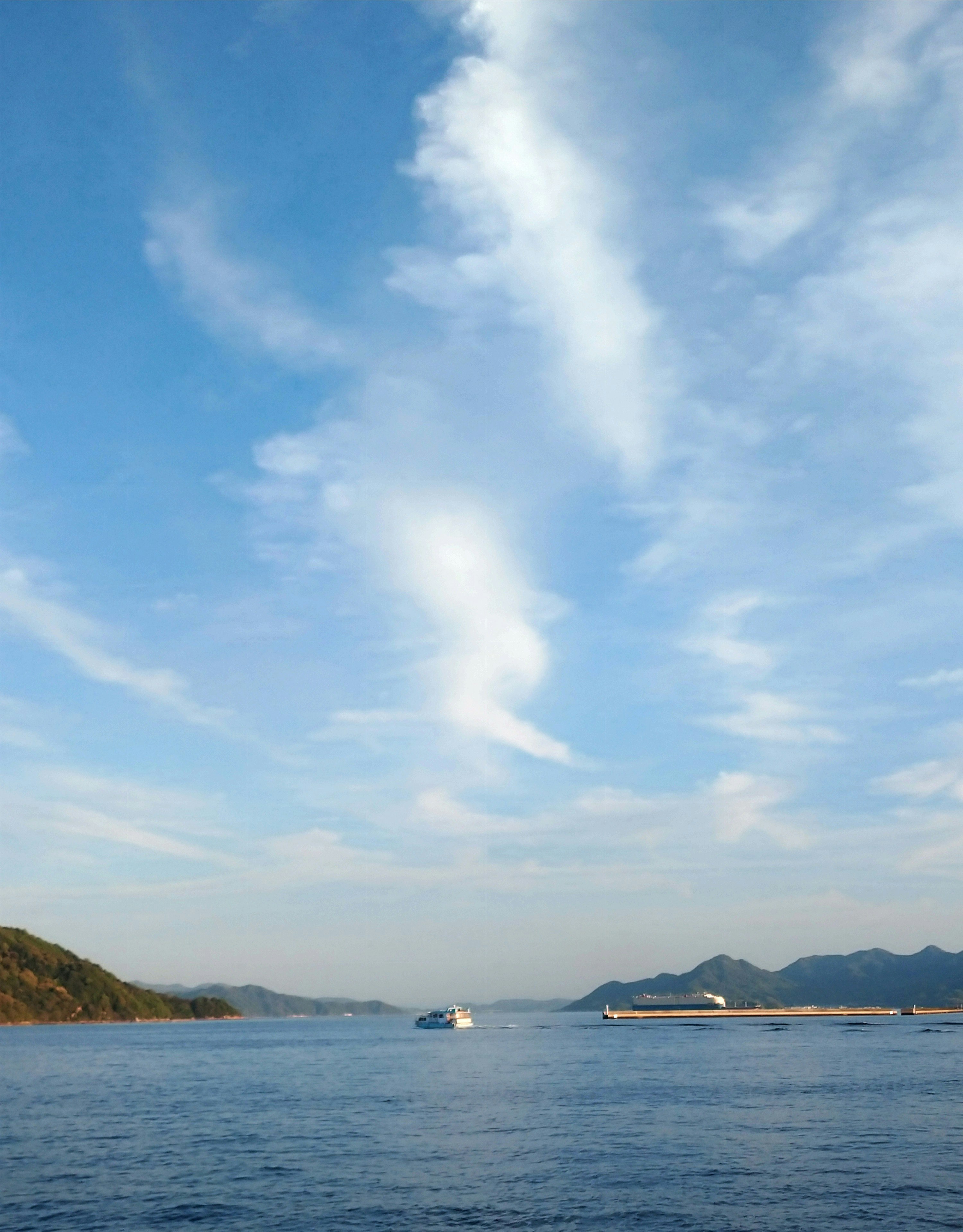 穏やかな海と遠くの山並みを見渡す青空の風景