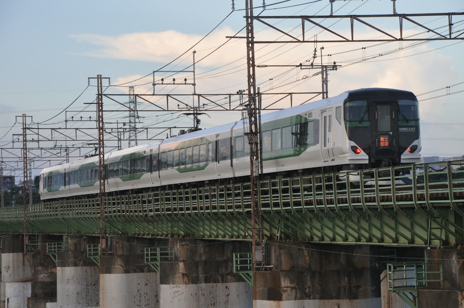 A modern train traveling over a bridge with electrical infrastructure