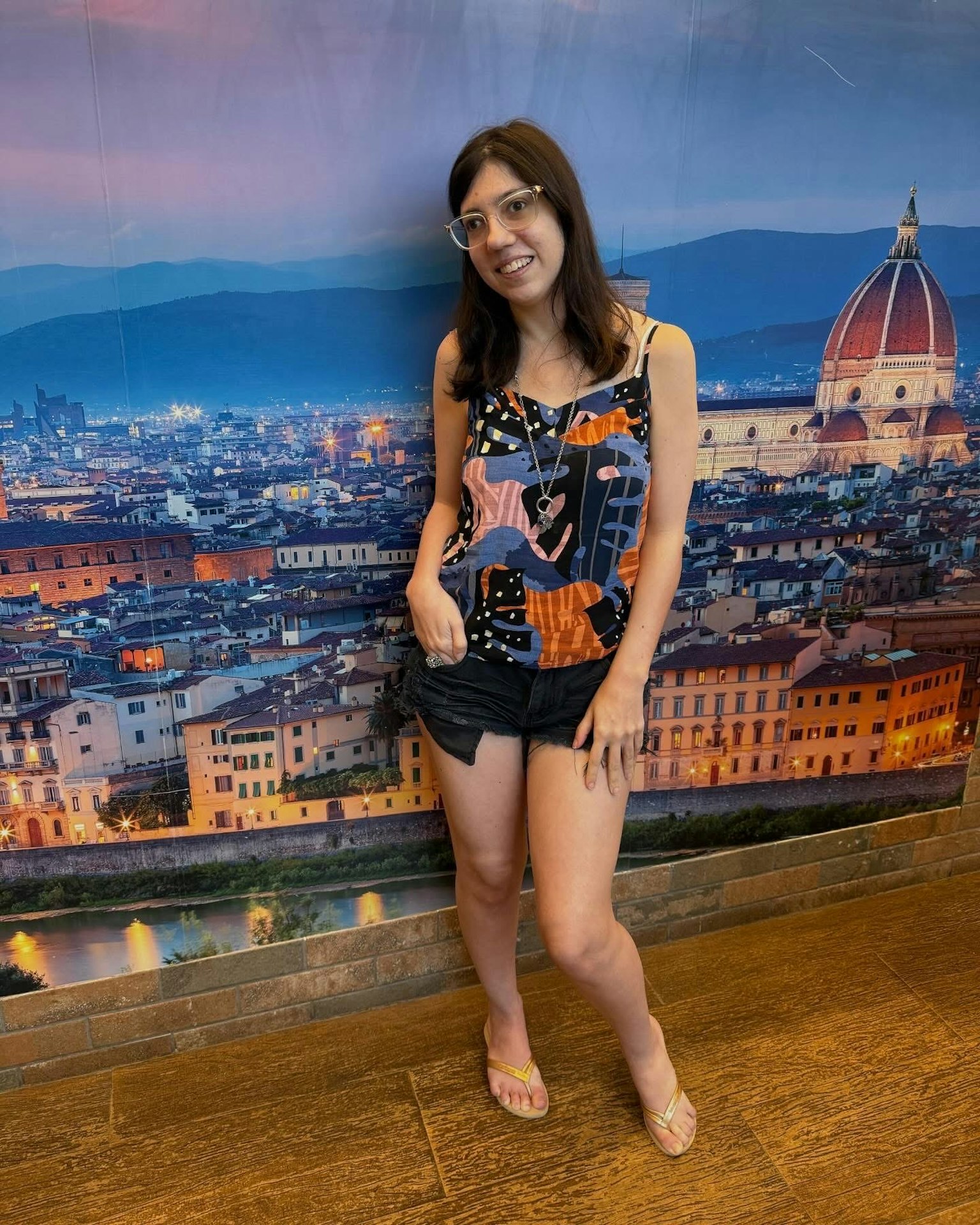 フィレンツェの背景でポーズをとる女性の写真　カラフルな服装とメガネを着用