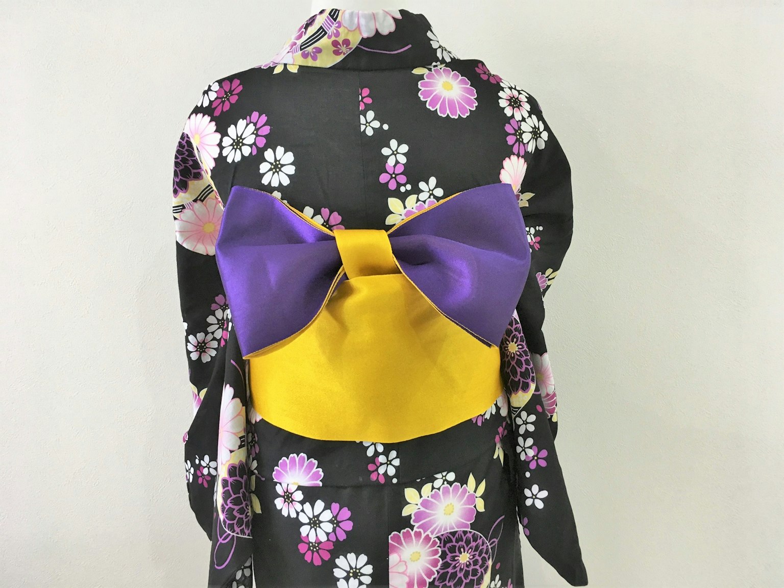 Tampilan belakang kimono dengan pita besar ungu dan kuning