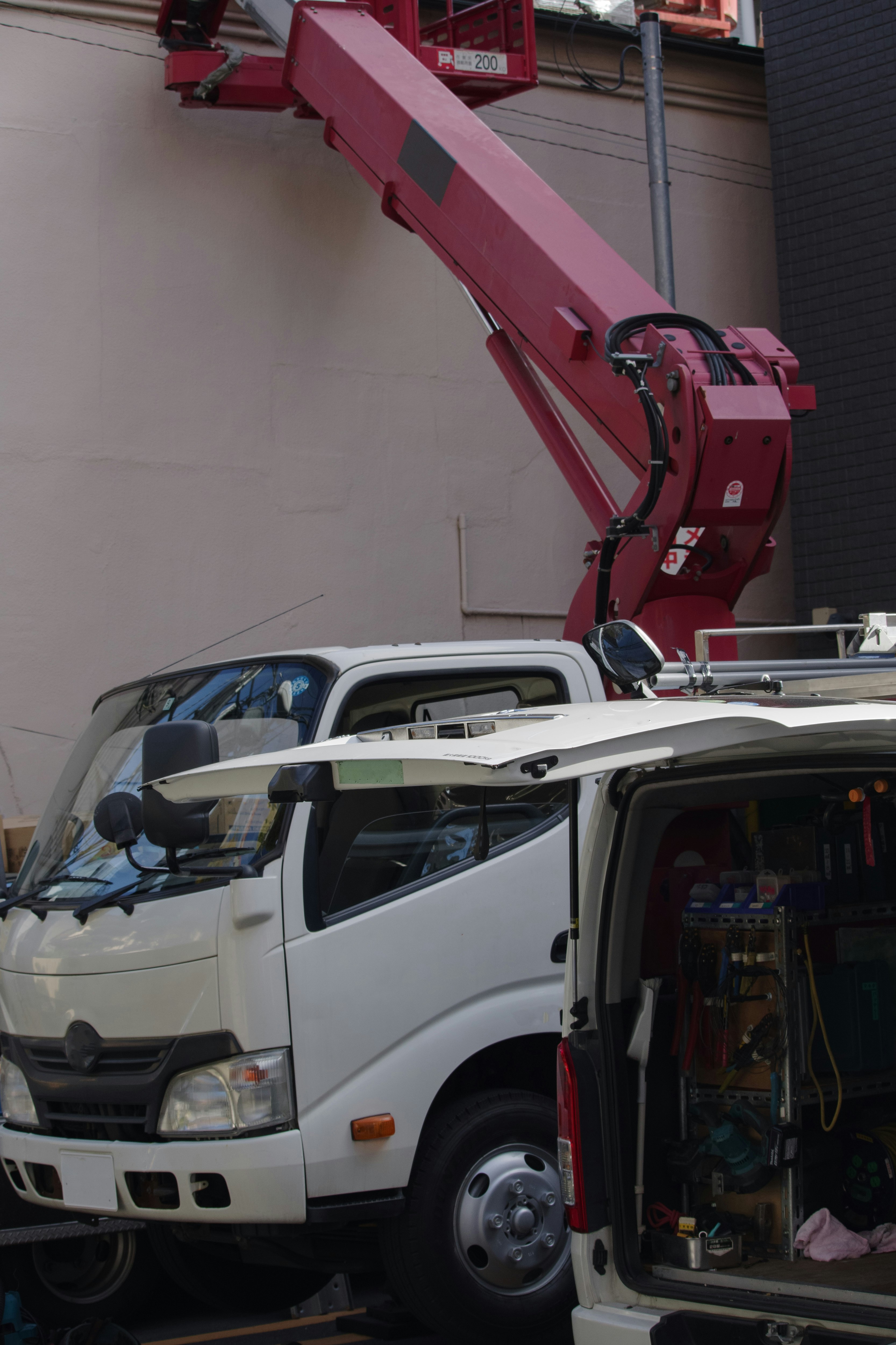 赤いクレーンと作業車が並ぶ工事現場の車両