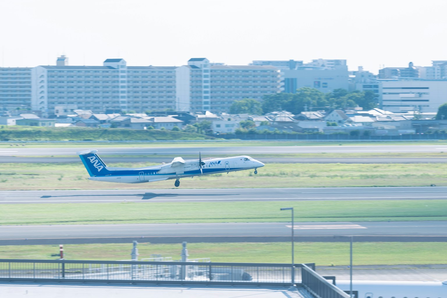 Kleines Flugzeug landet auf der Landebahn mit Stadt im Hintergrund
