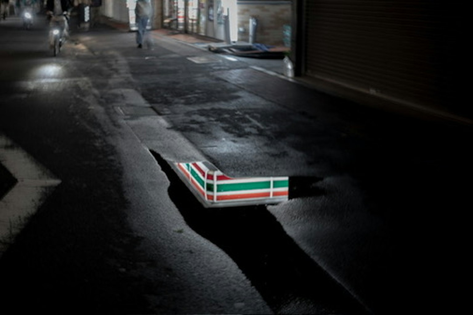 Un buco in una strada buia con un'insegna Seven Eleven