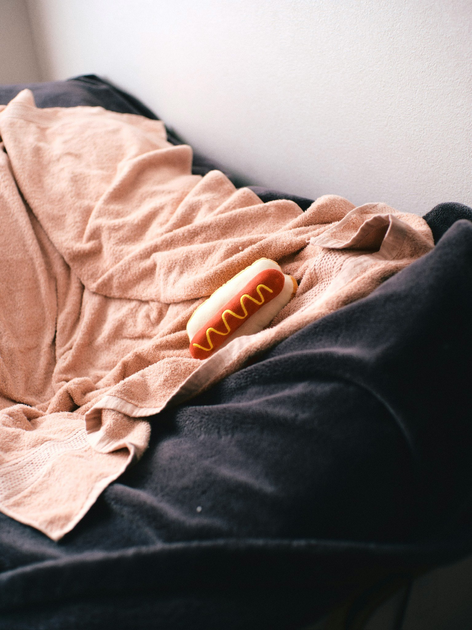 A hot dog resting on a beige blanket on a couch