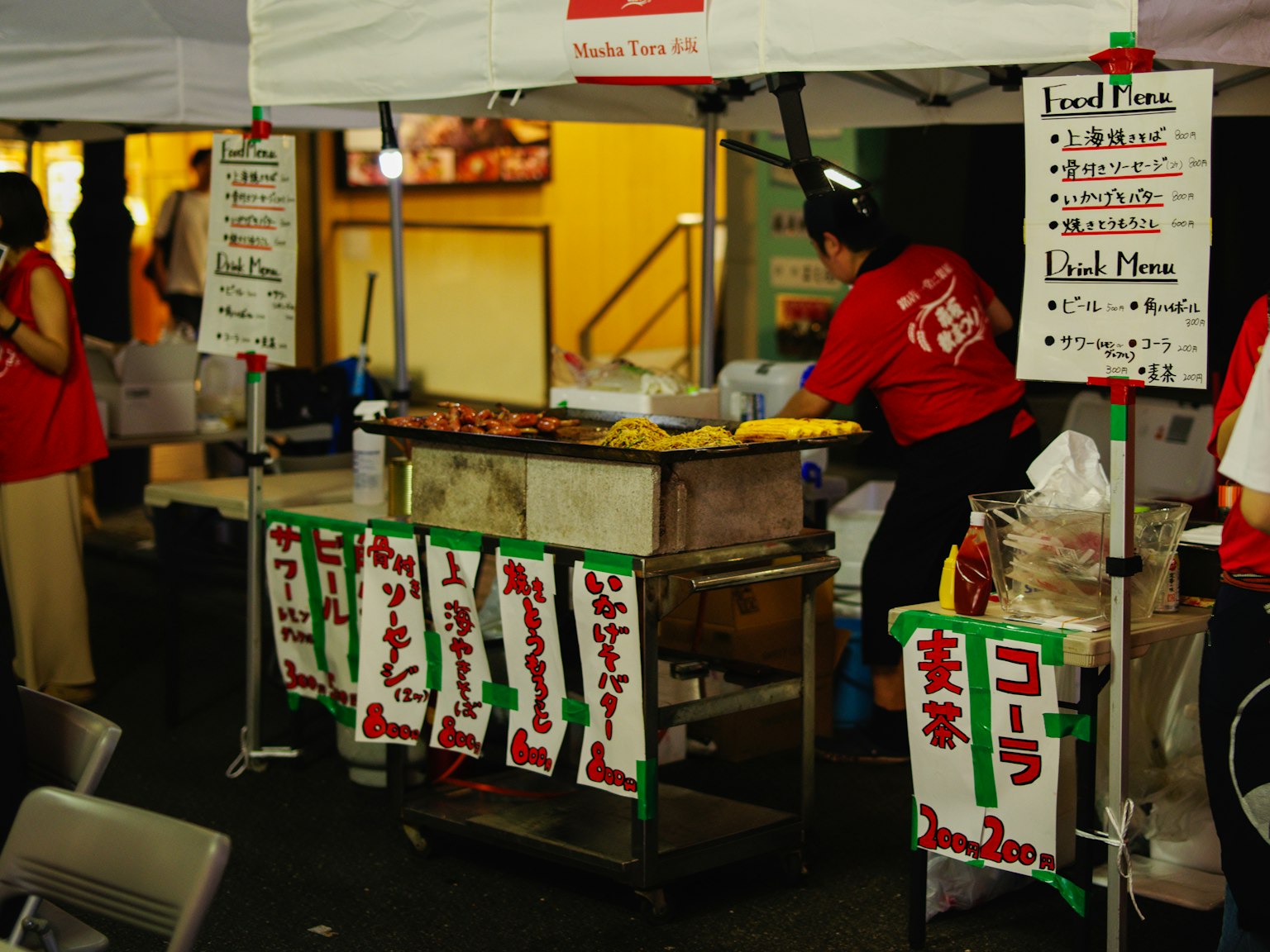 Chiosco di cibo a un festival con un venditore in camicia rossa che serve piatti