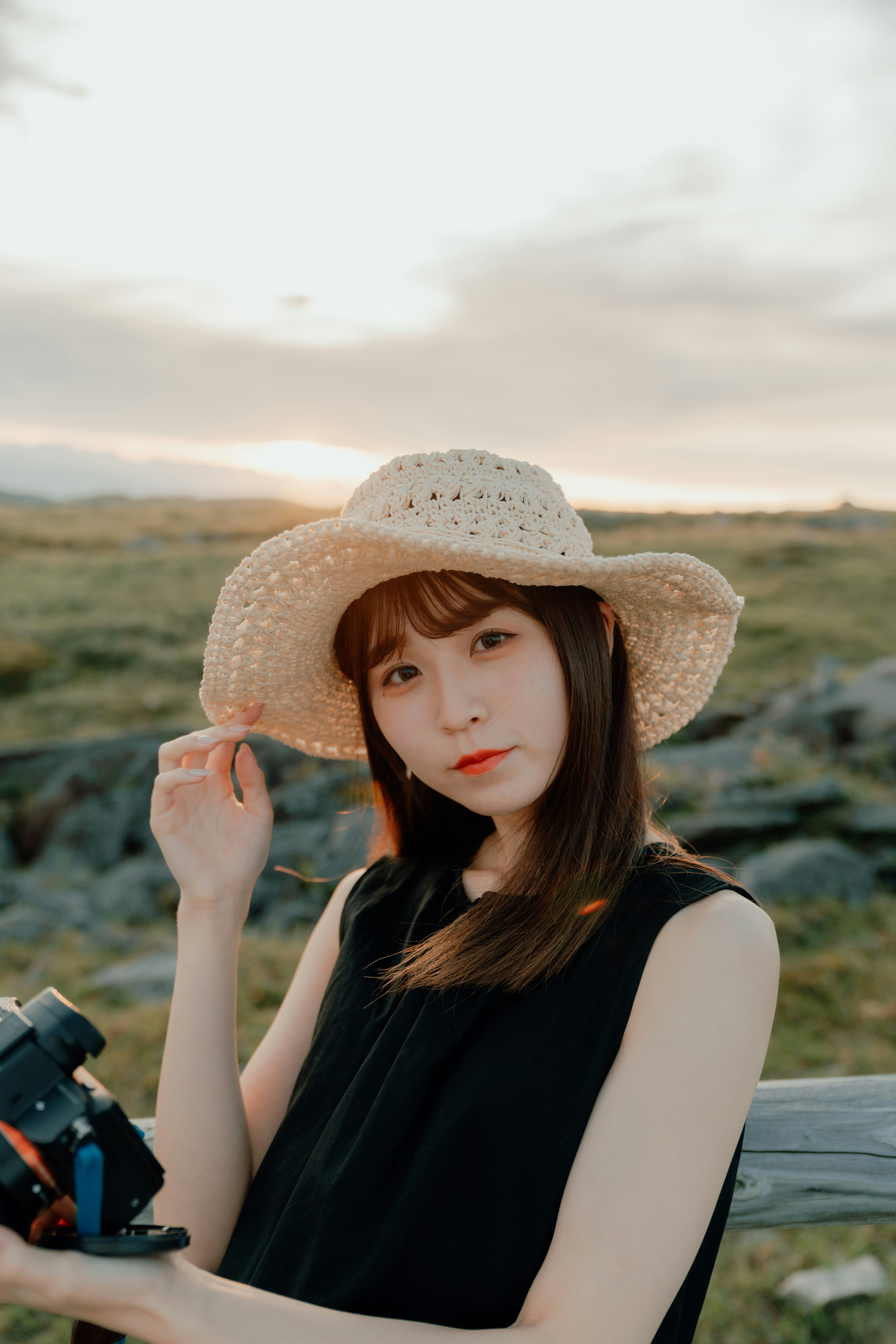 草原の丘を背景に麦わら帽子の女性