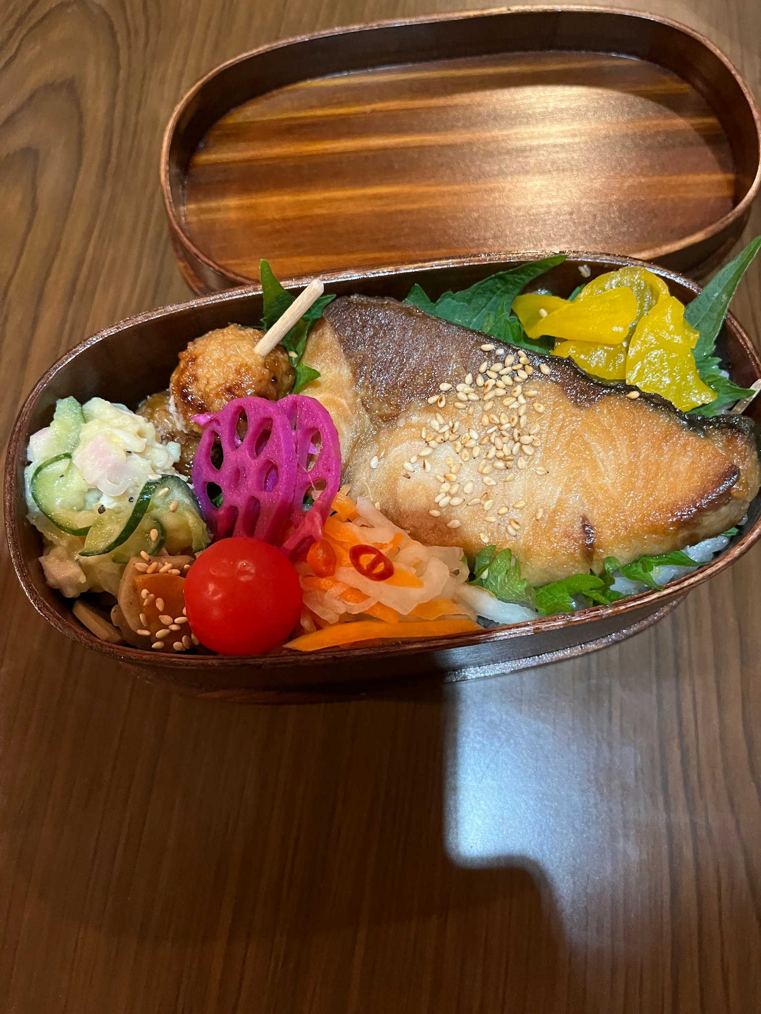 Une boîte à bento magnifiquement présentée avec du saumon et des plats d'accompagnement colorés