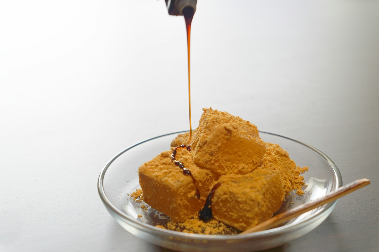 Sweet tofu topped with yellow soybean flour and drizzled with black syrup
