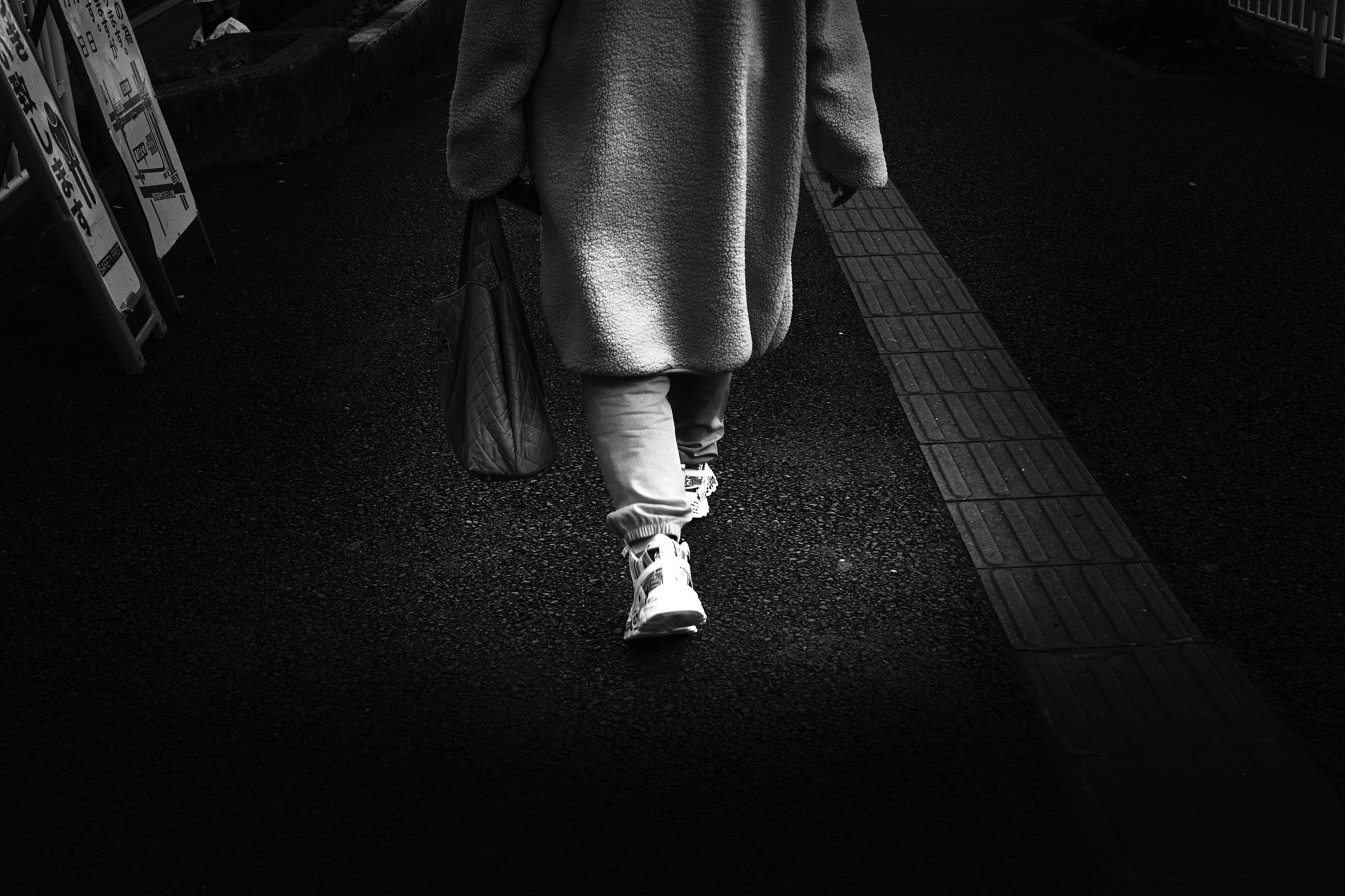 rear view of a person walking along a sidewalk