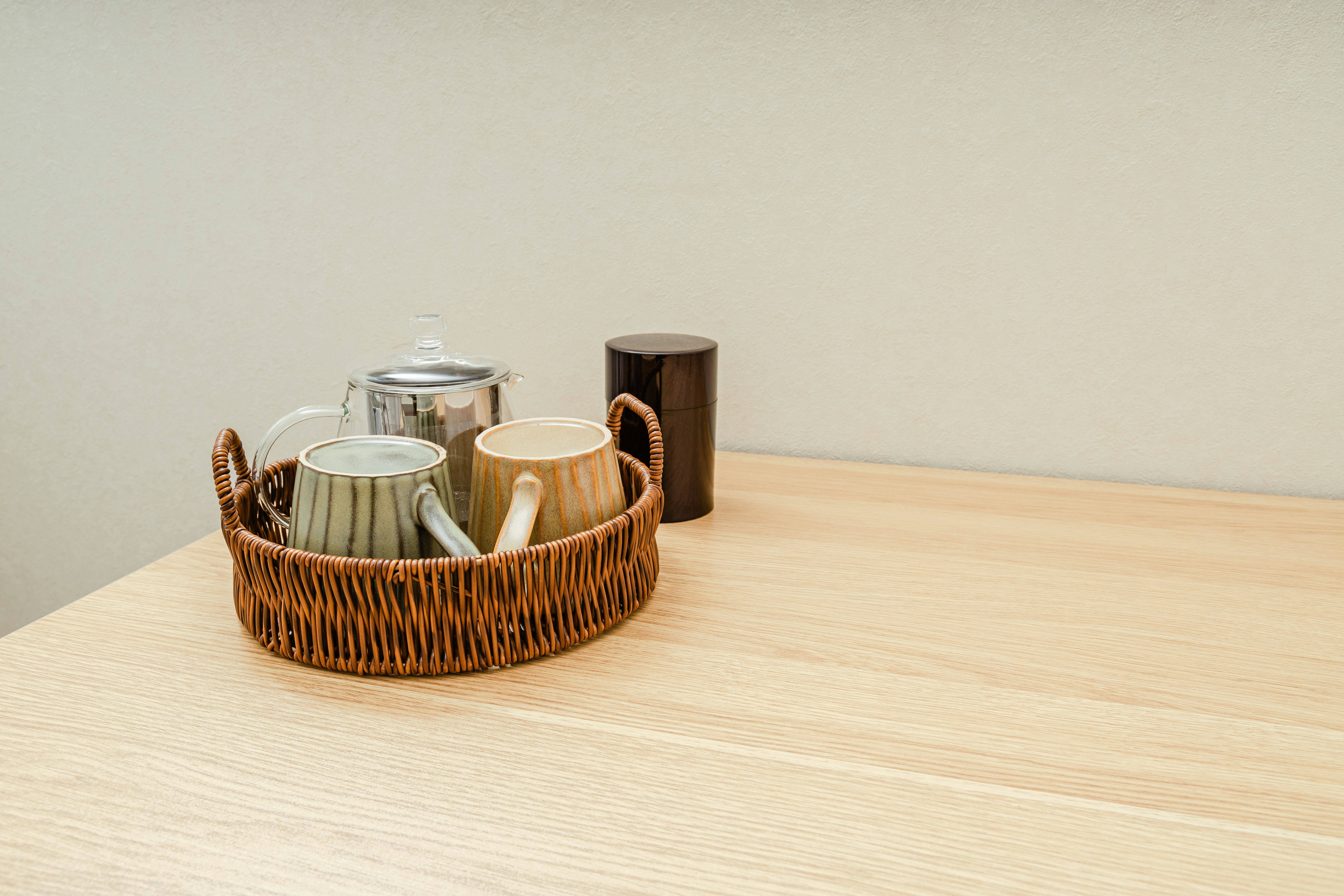 籠に入った急須と湯呑みのあるお茶のテーブル
